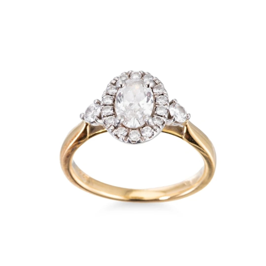 A DIAMOND CLUSTER RING, the central oval cut diamond to a di...