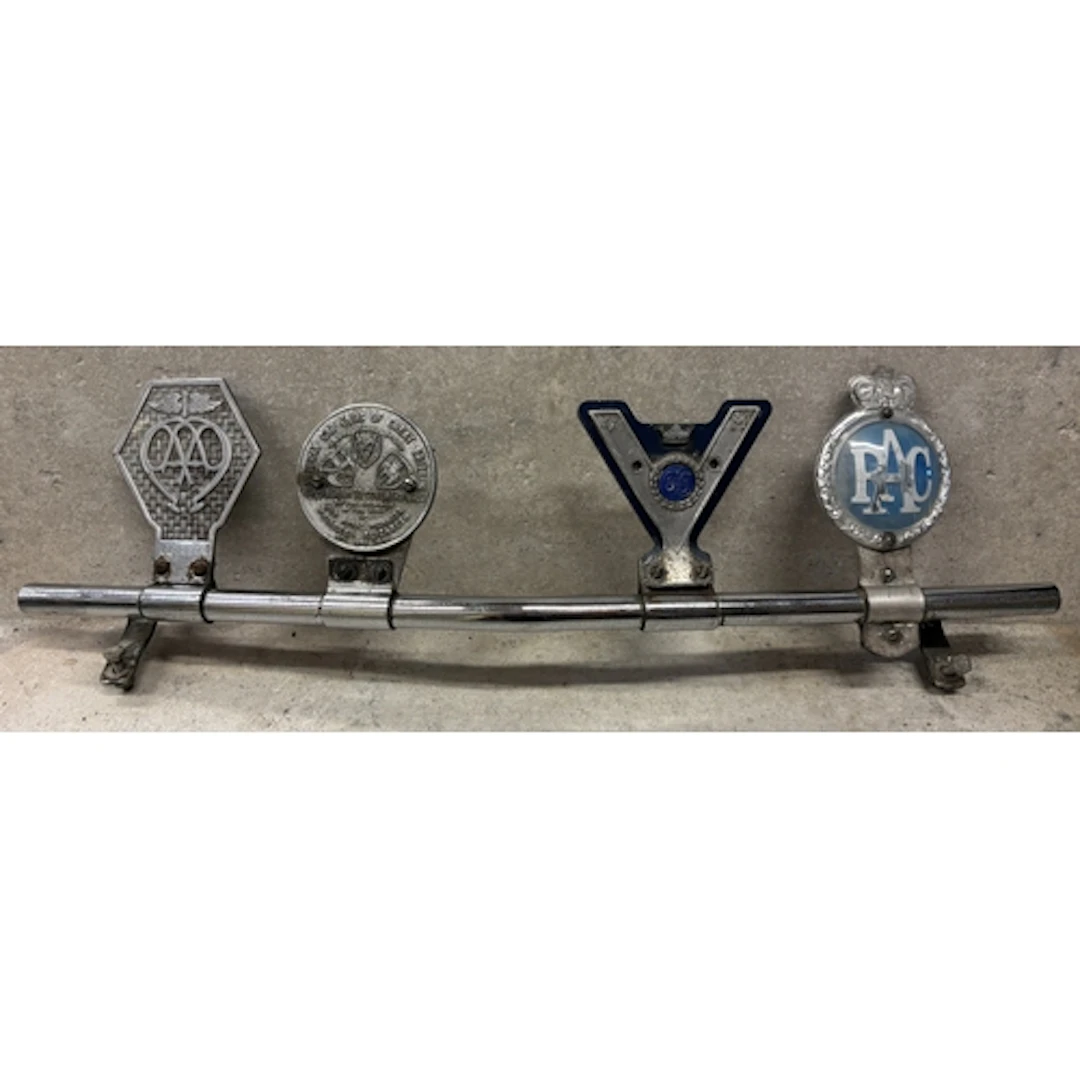 A vintage badge bar fitted with four badges to include AA Co...
