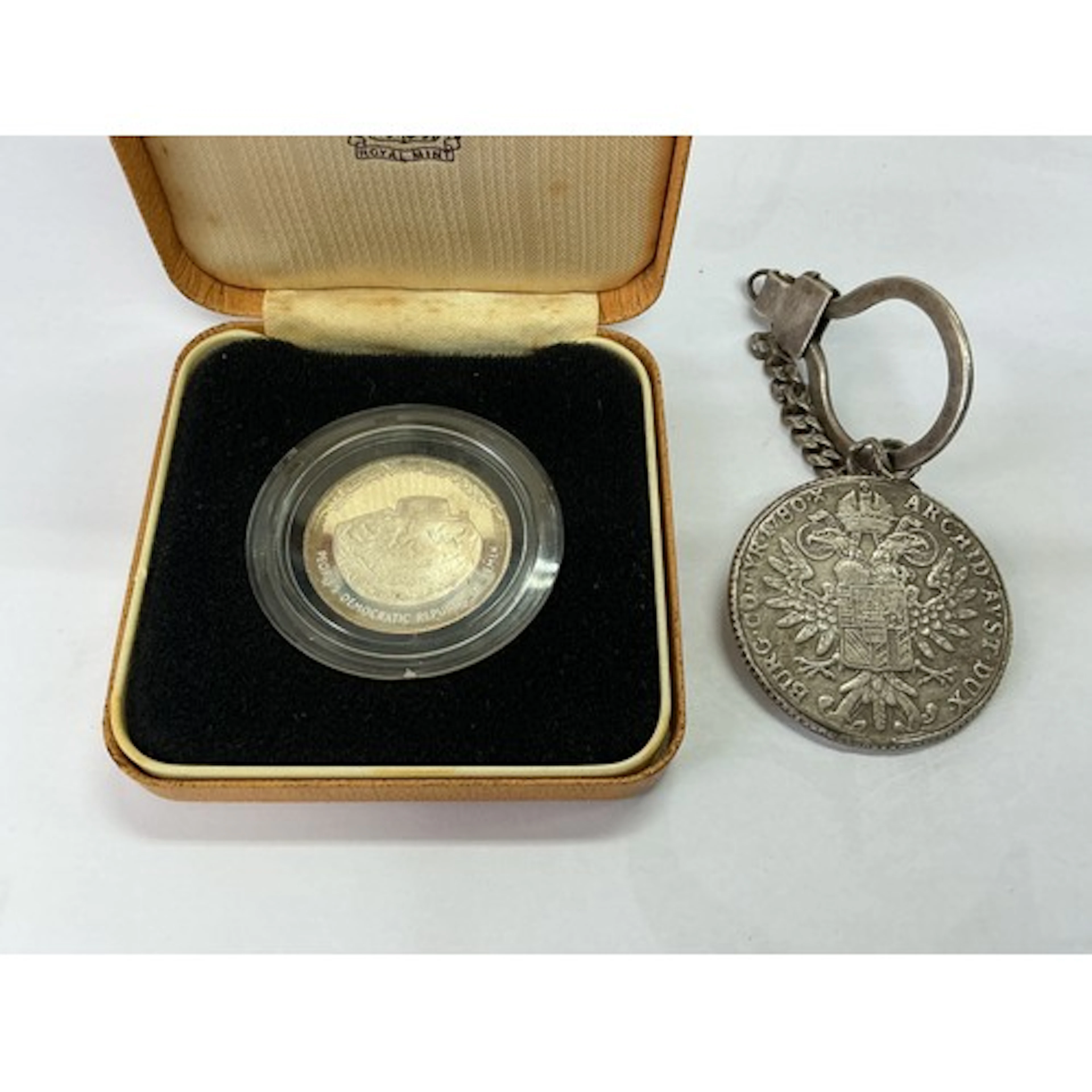 A cased 1977 Yemen coin plus a continental coin suspended on...