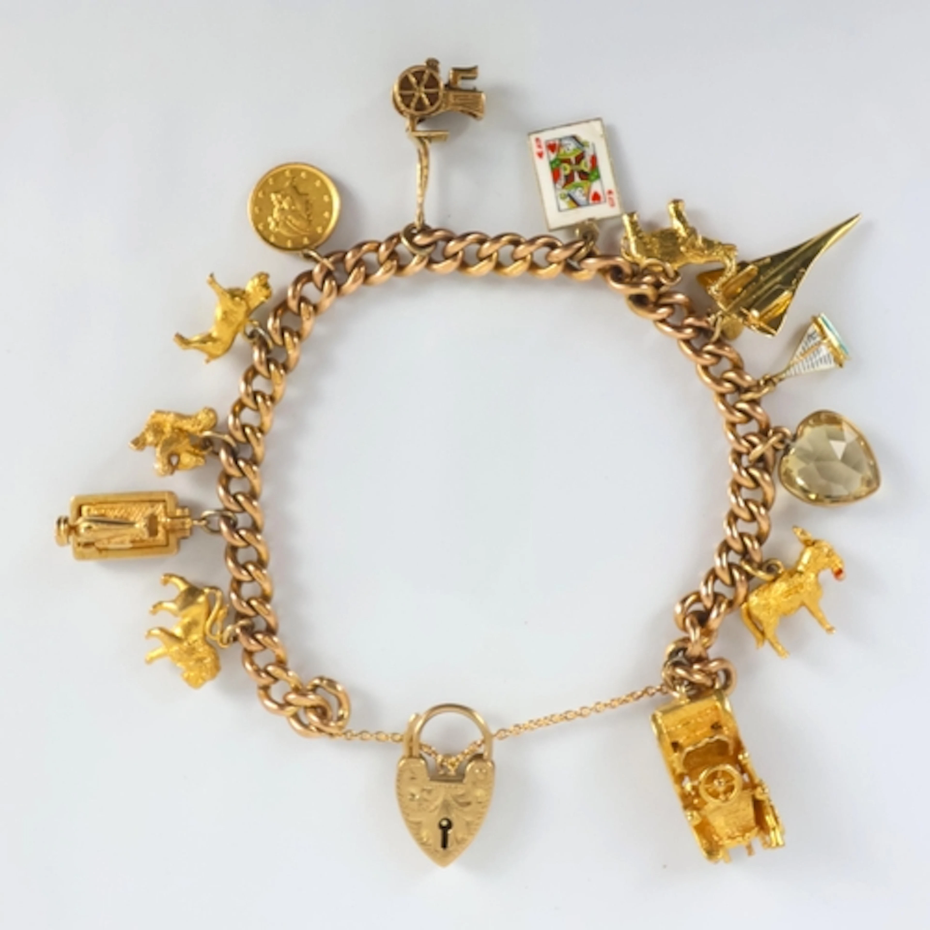 A yellow metal charm bracelet, the curb link bracelet suspen...
