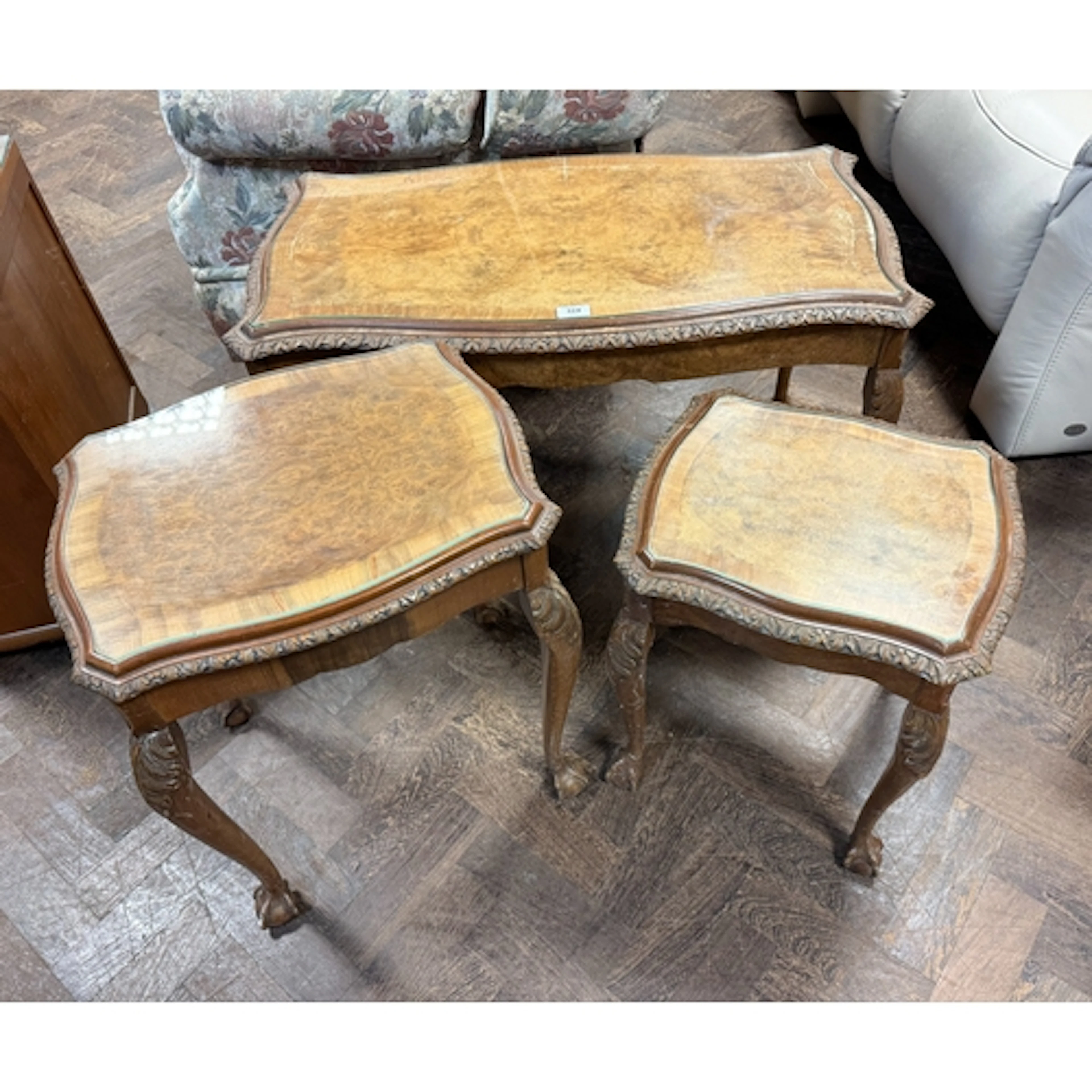 A set of three burr walnut coffee tables standing on claw an...