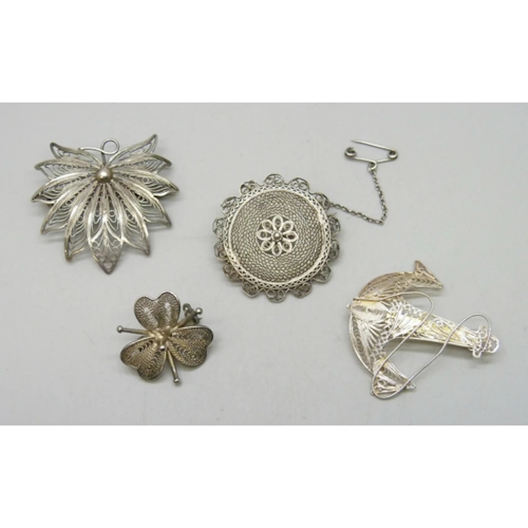 Three white metal filigree brooches, and a silver example, 1...