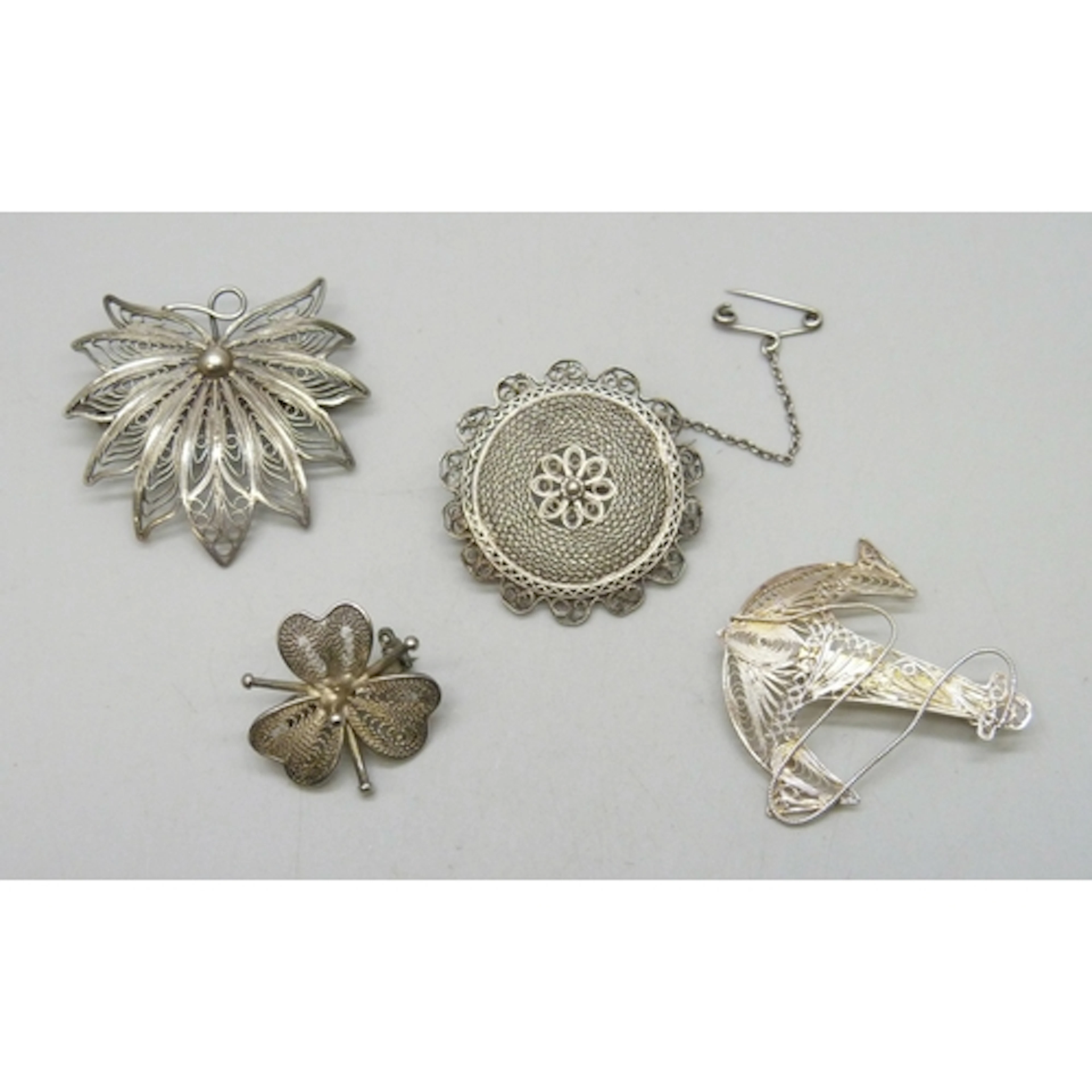 Three white metal filigree brooches, and a silver example, 1...