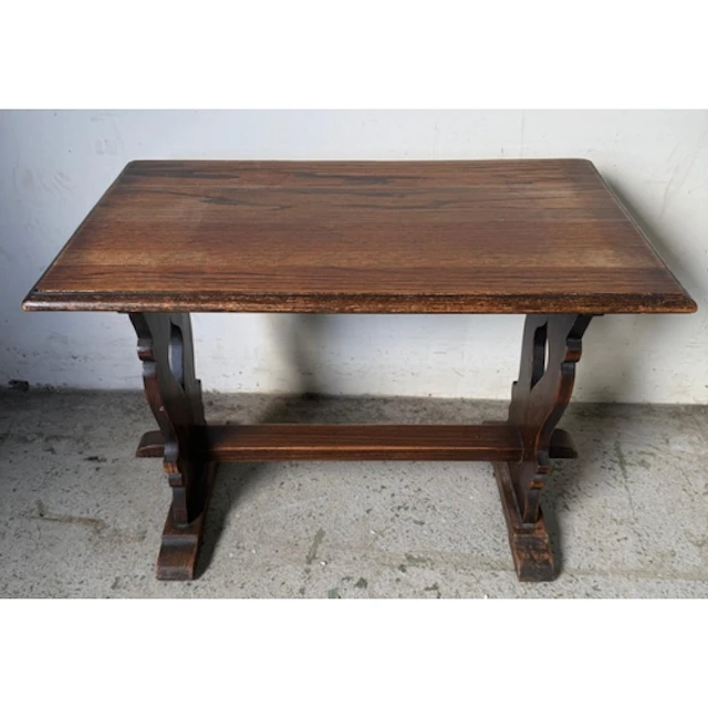 An Oak trestle side table with shaped supports and peg ends...