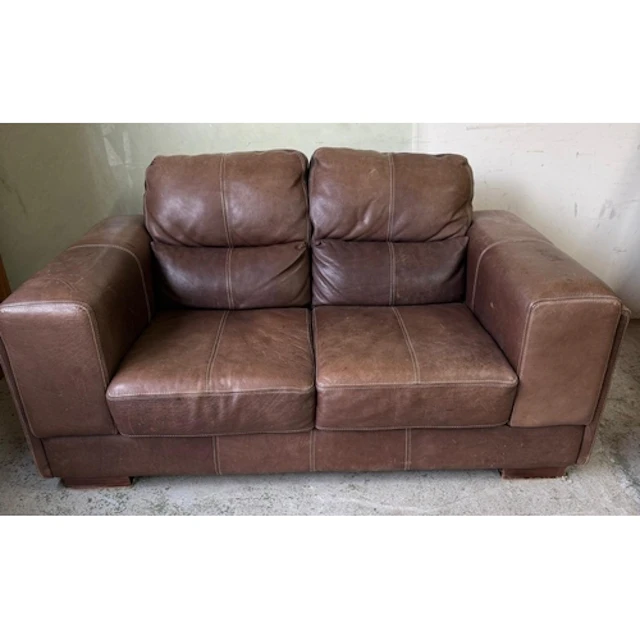 A brown leather two seater sofa on block feet. Back height 8...