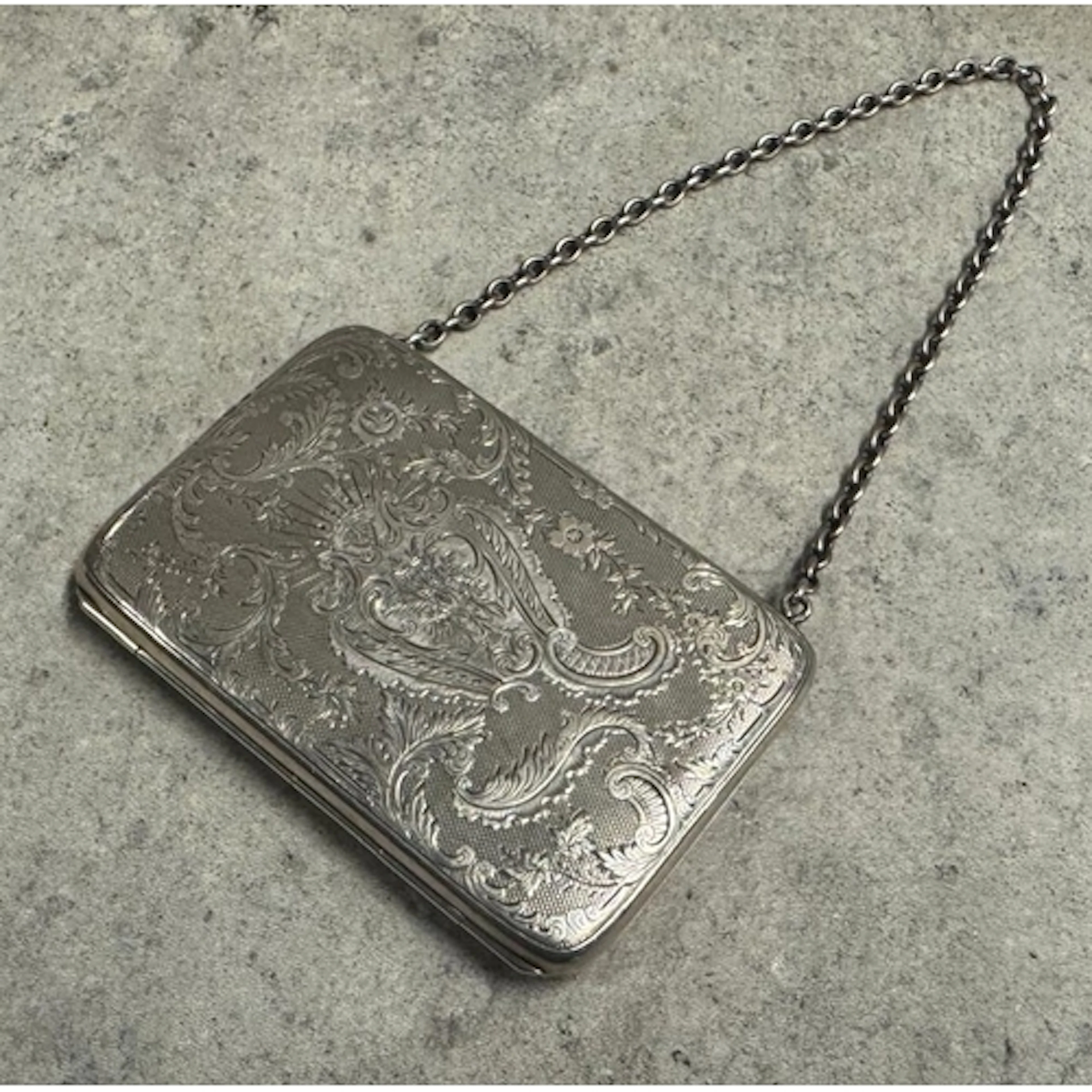 An engraved Victorian silver card holder with engraved decor...