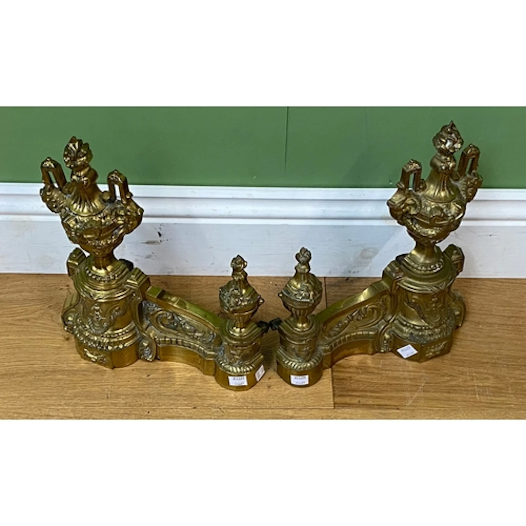 A pair of gilt metal fire dogs with urn finials