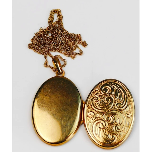 A 9ct gold oval locket with foliate scroll decoration and on...