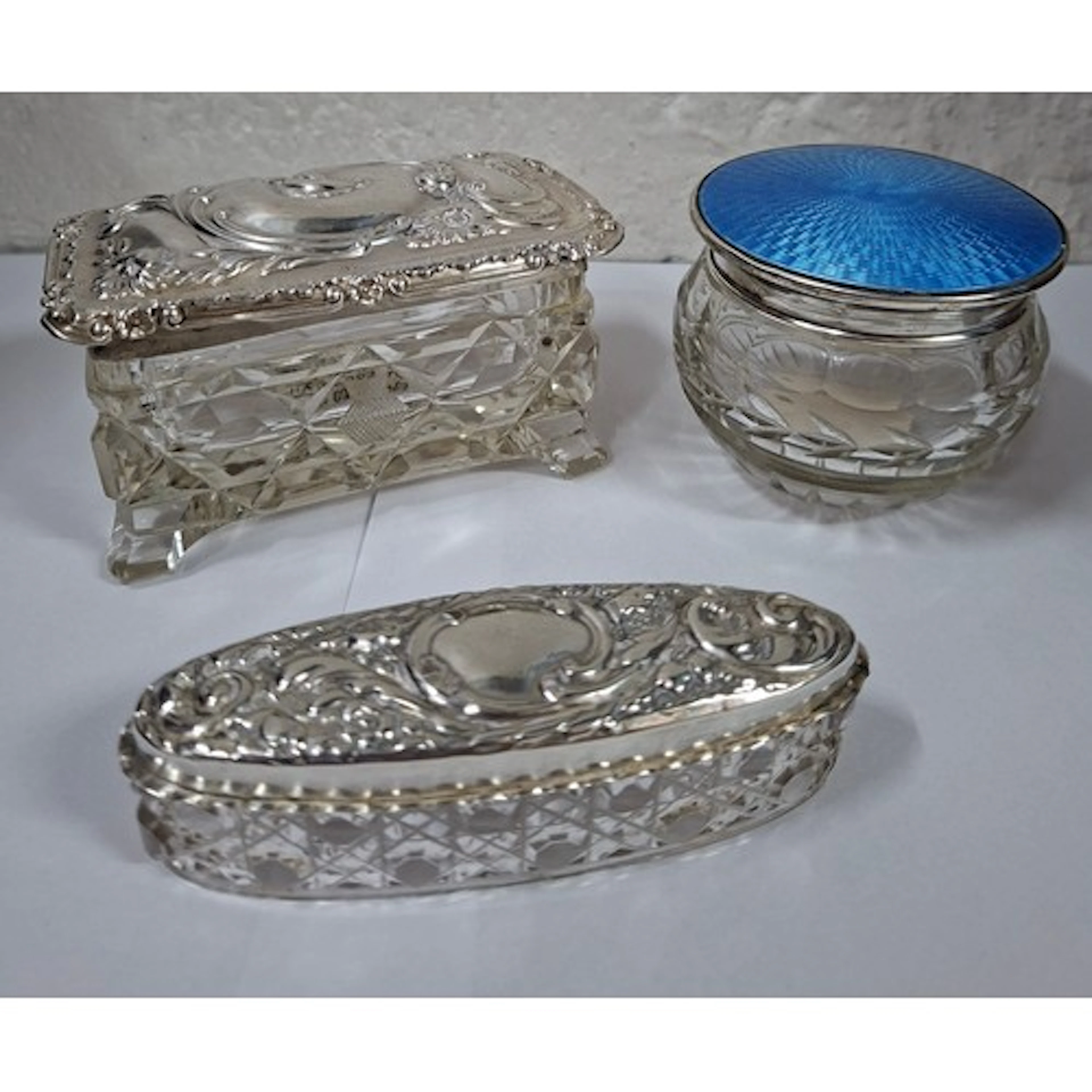 Three glass dressing table pots, one having a silver and blu...
