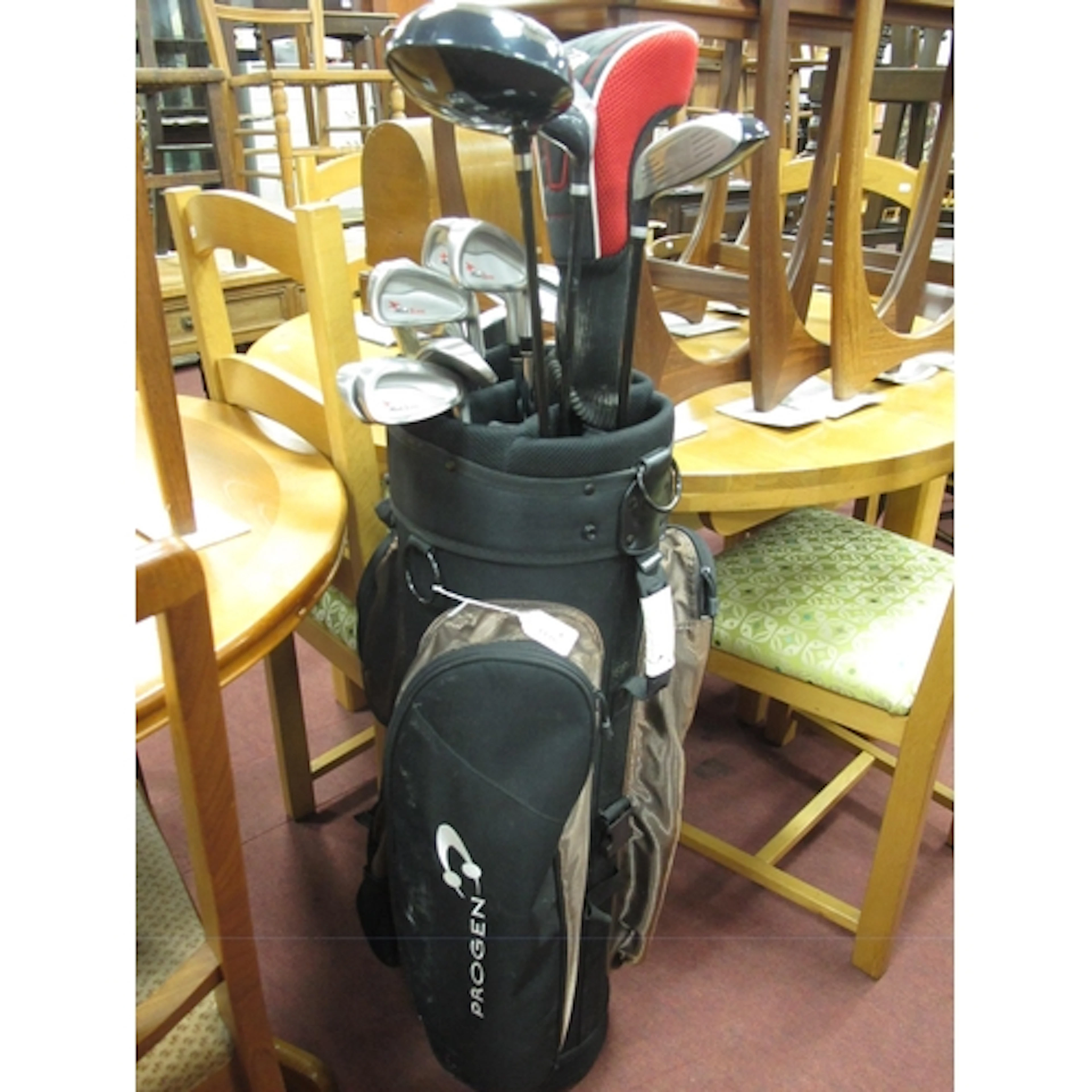 Mixed set of golf clubs in a black and bronze Progen cart ba...