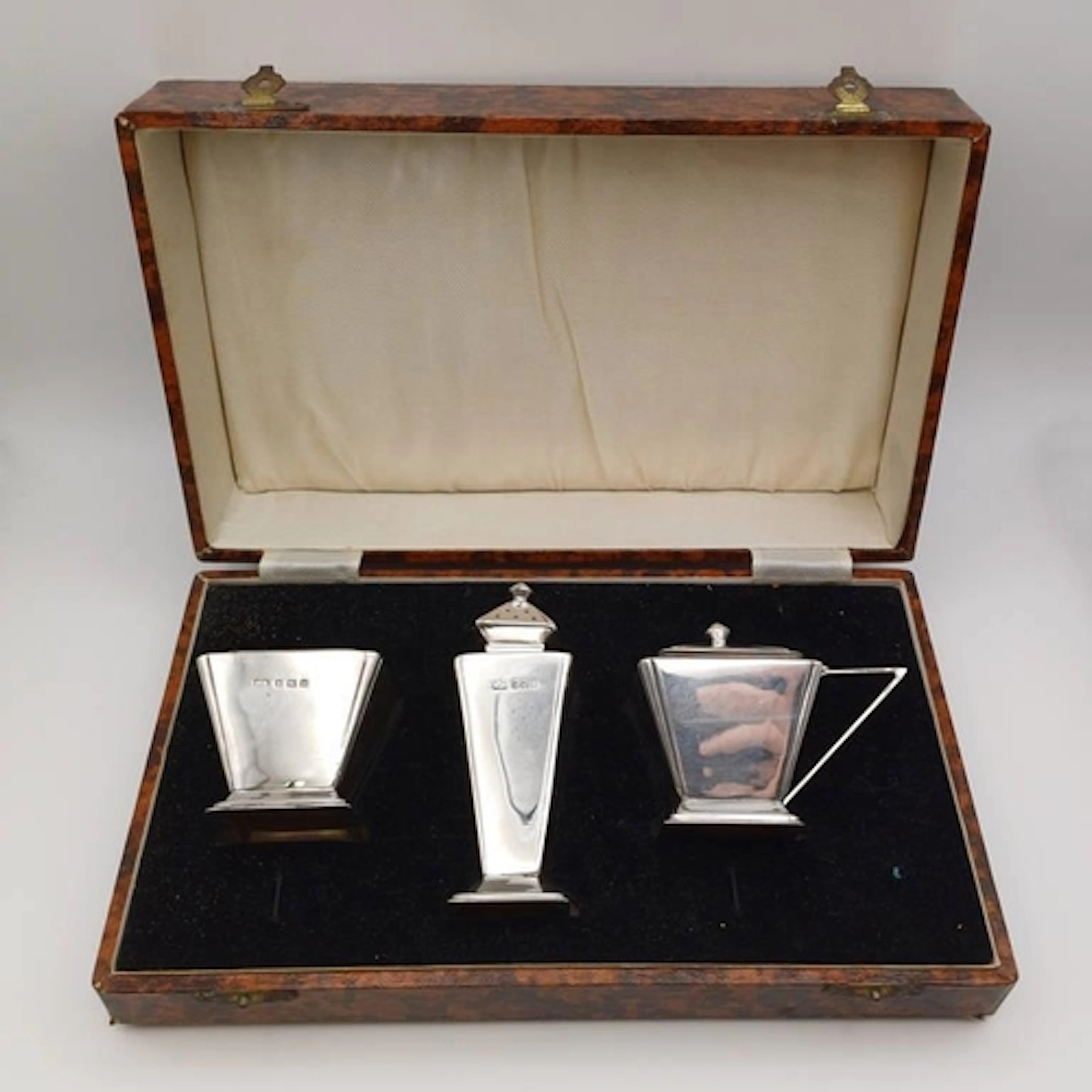 AN ART DECO SILVER 3 PIECE CASED CRUET SET WITH BLUE GLASS L...