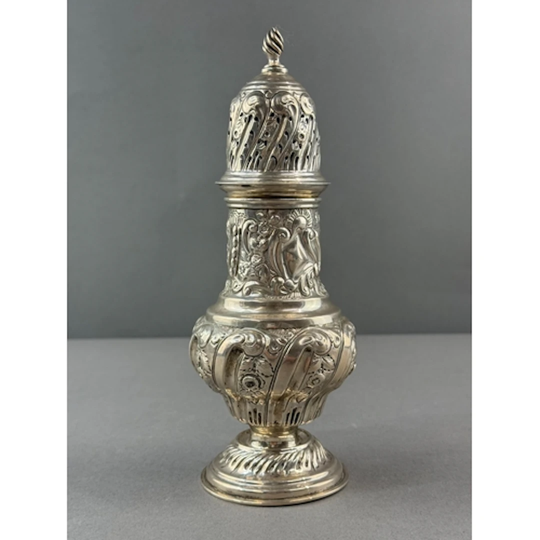 Silver: a baluster caster with leaf and flower repousse deco...