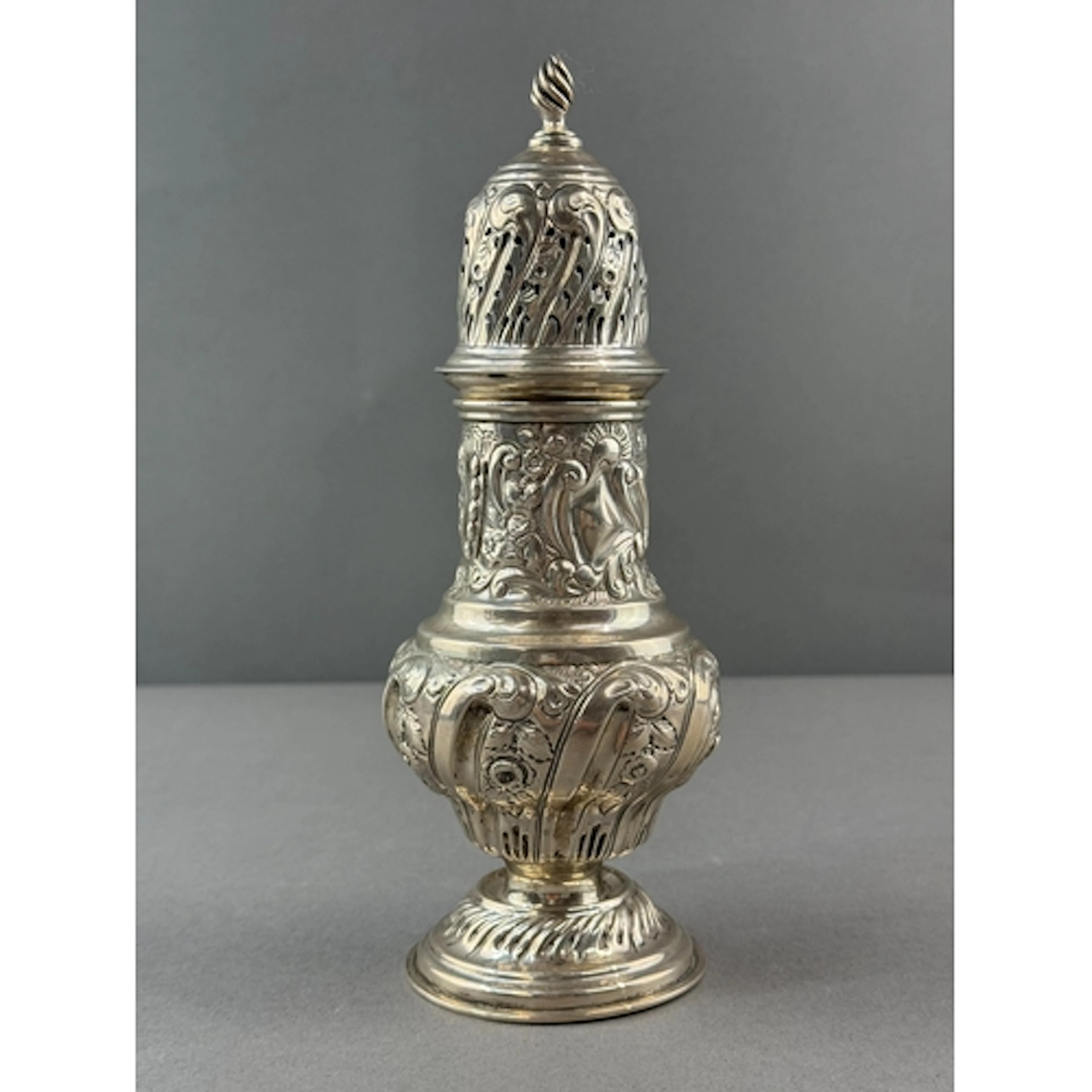 Silver: a baluster caster with leaf and flower repousse deco...