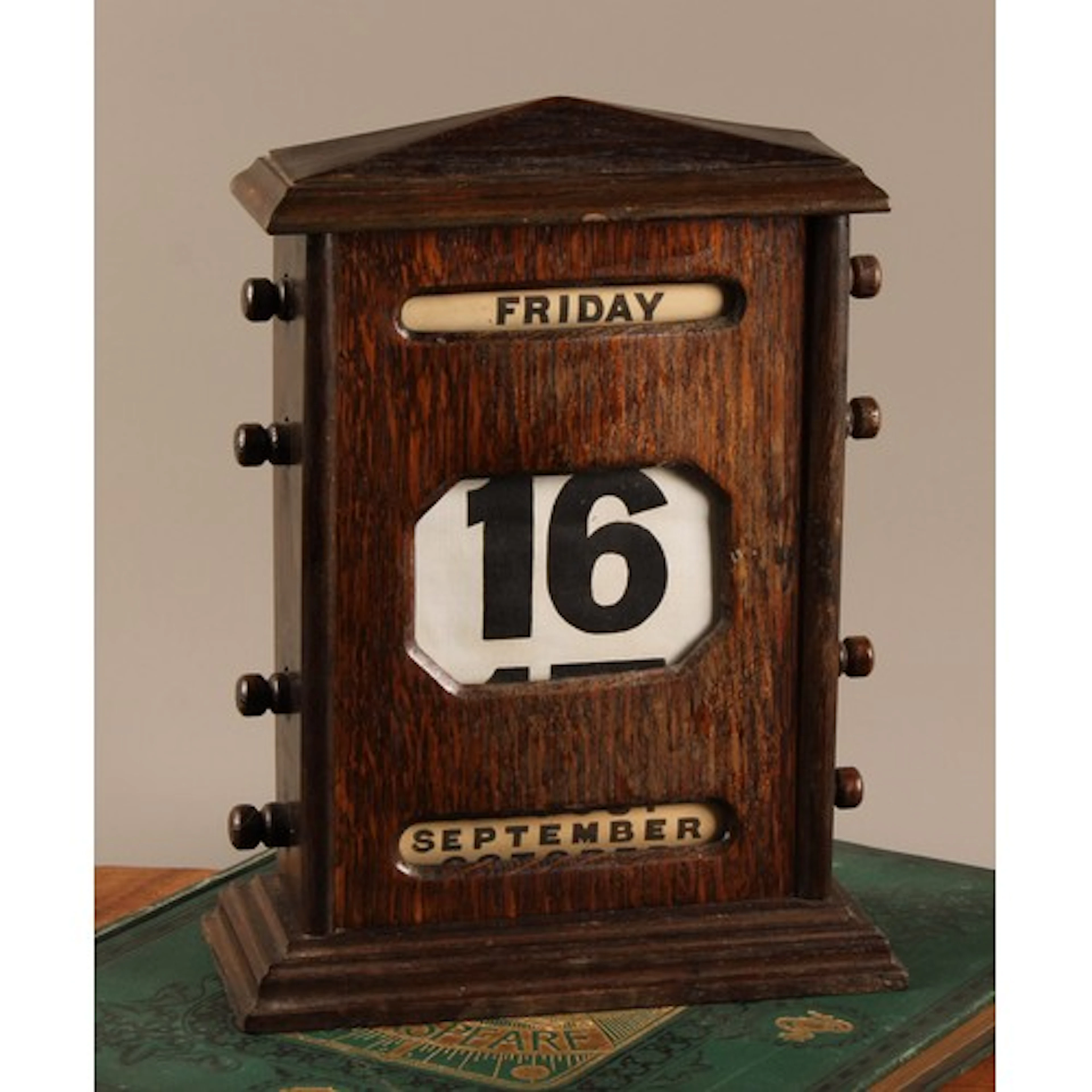 A large early 20th century oak perpetual desk calendar, sarc...