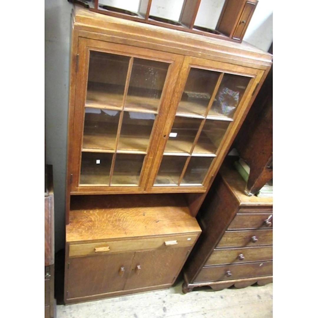 Cotswold School oak bookcase, the stepped cornice above a pa...