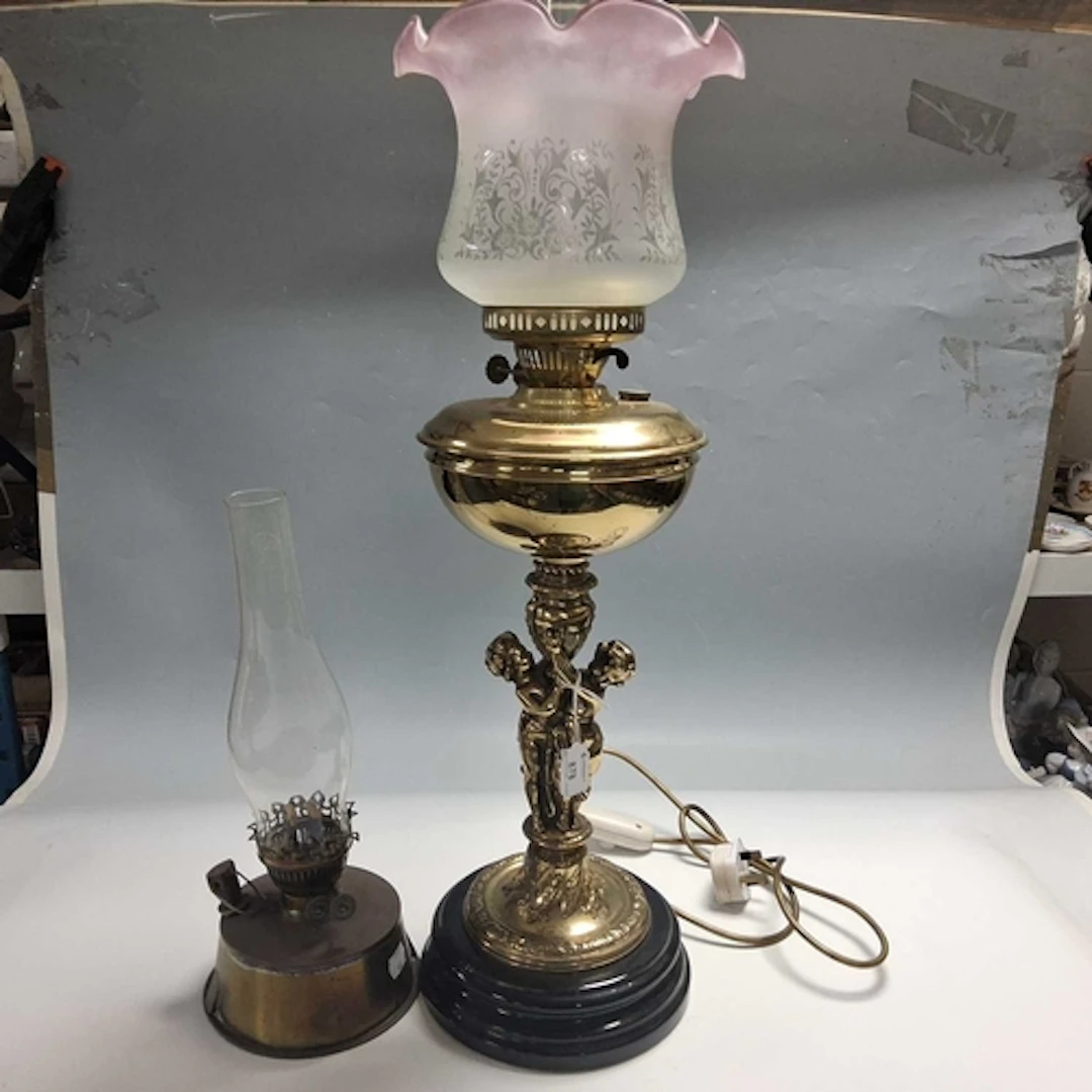 TWO OIL LAMPS comprising a figural style lamp with a brass r...
