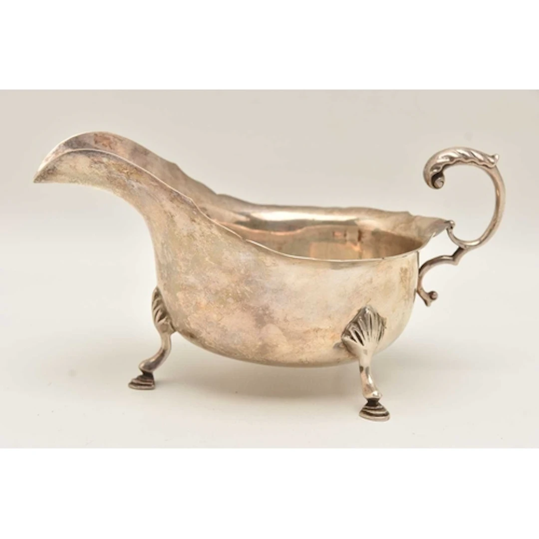 AN EARLY 20TH CENTURY SILVER SAUCE BOAT, with wavy rim and s...