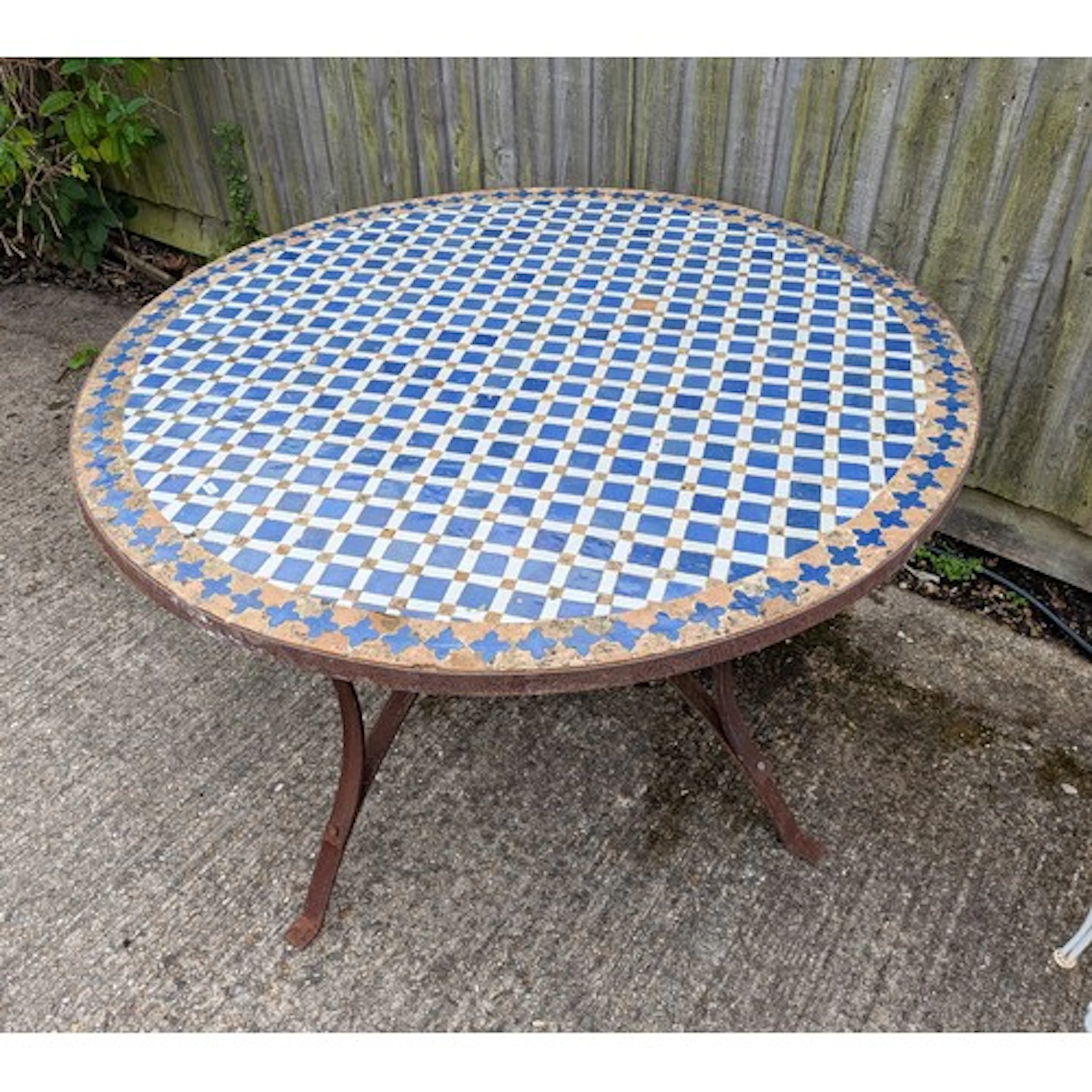 An antique style iron circular garden table with blue and wh...