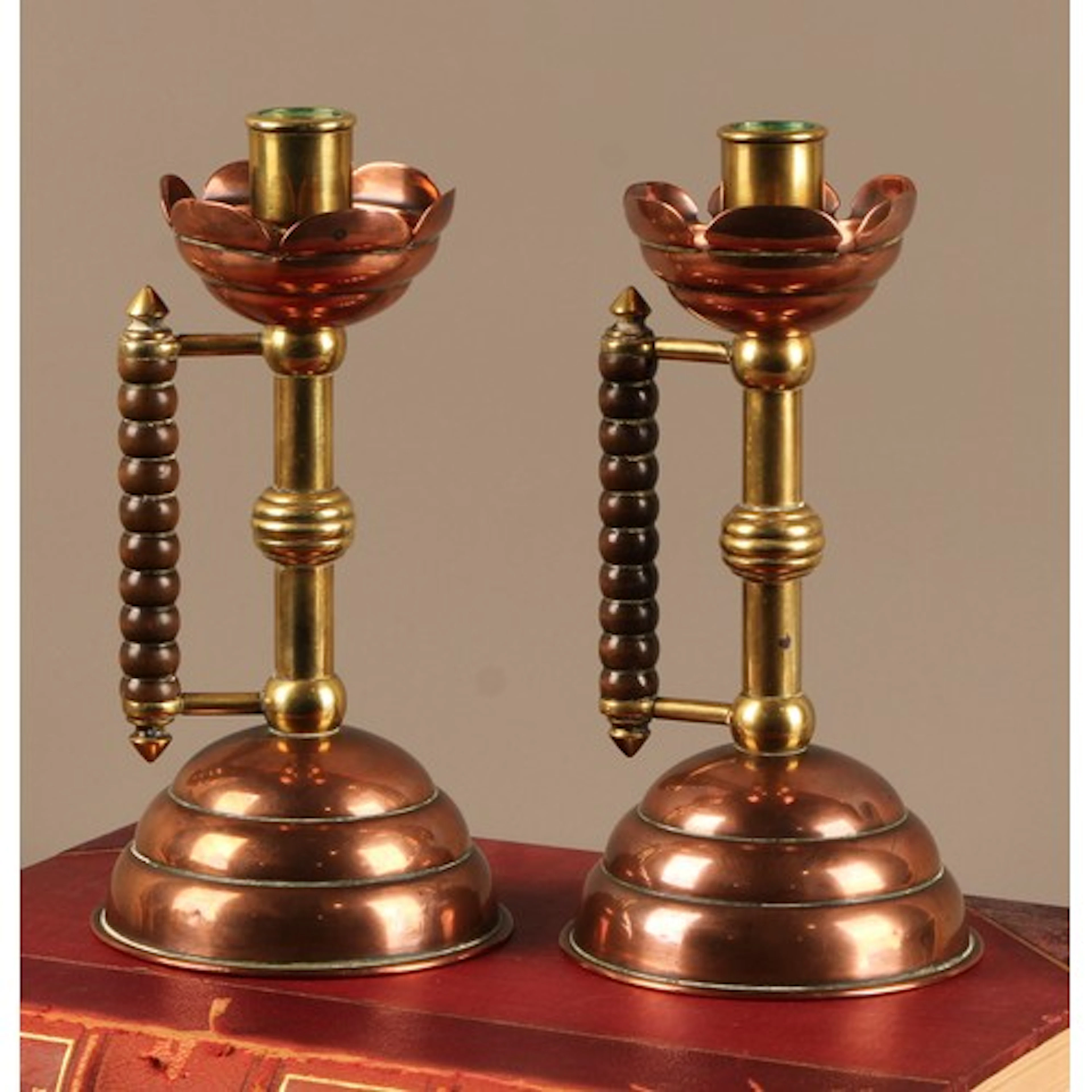 A pair of Arts & Crafts copper and brass candlesticks, in th...