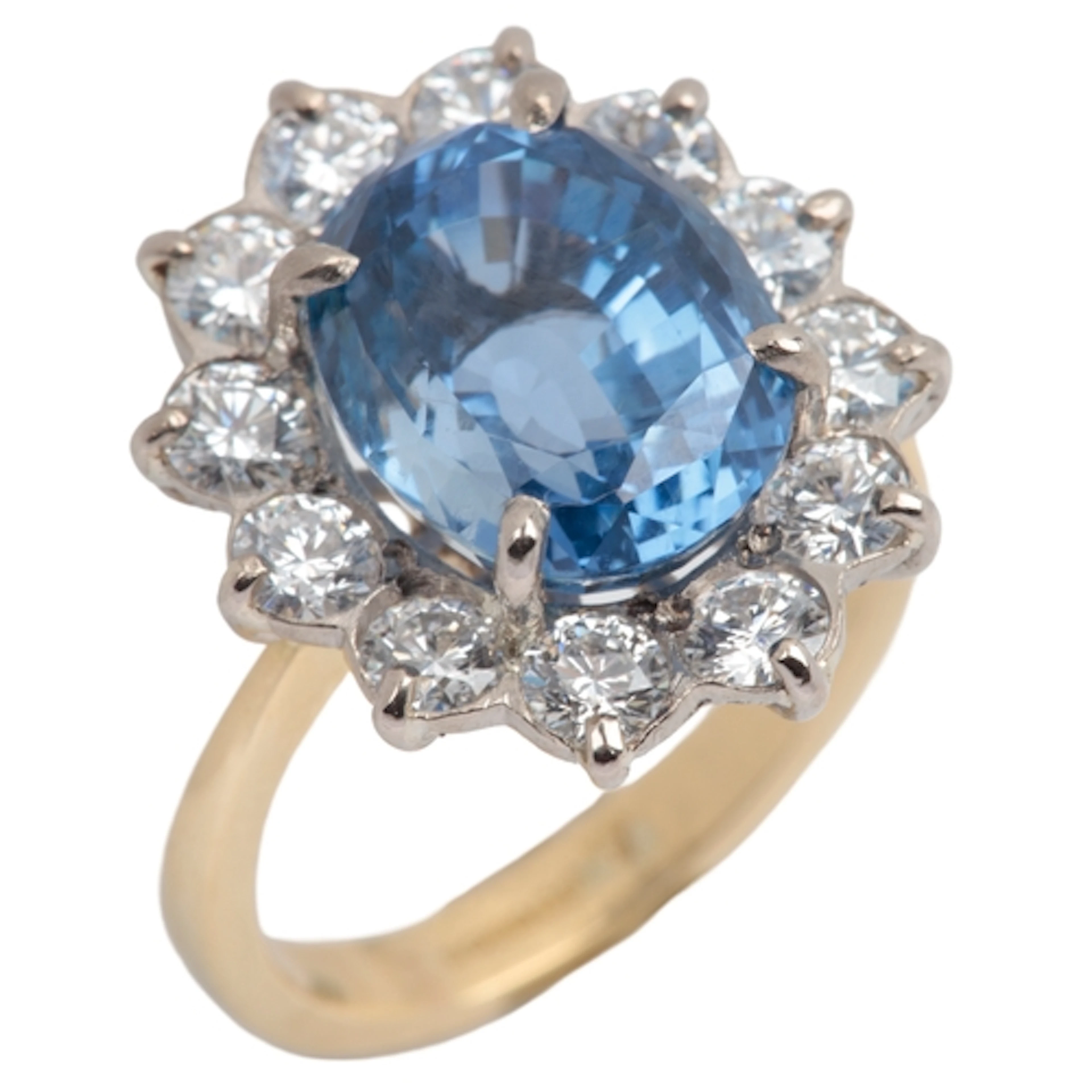 A sapphire and diamond cluster ring, claw-set with an oval s...