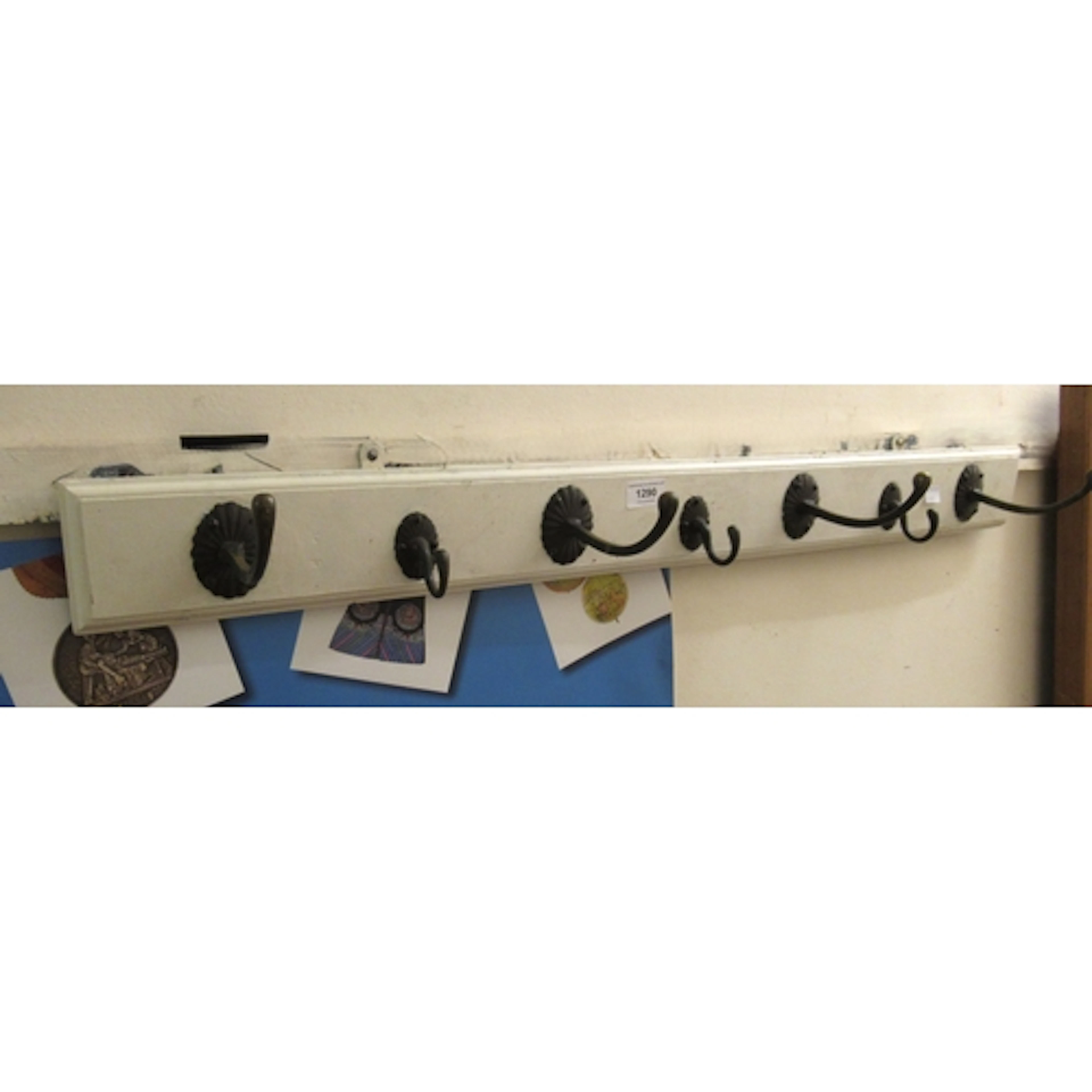 Set of seven antique copper coat hooks on white painted moul...