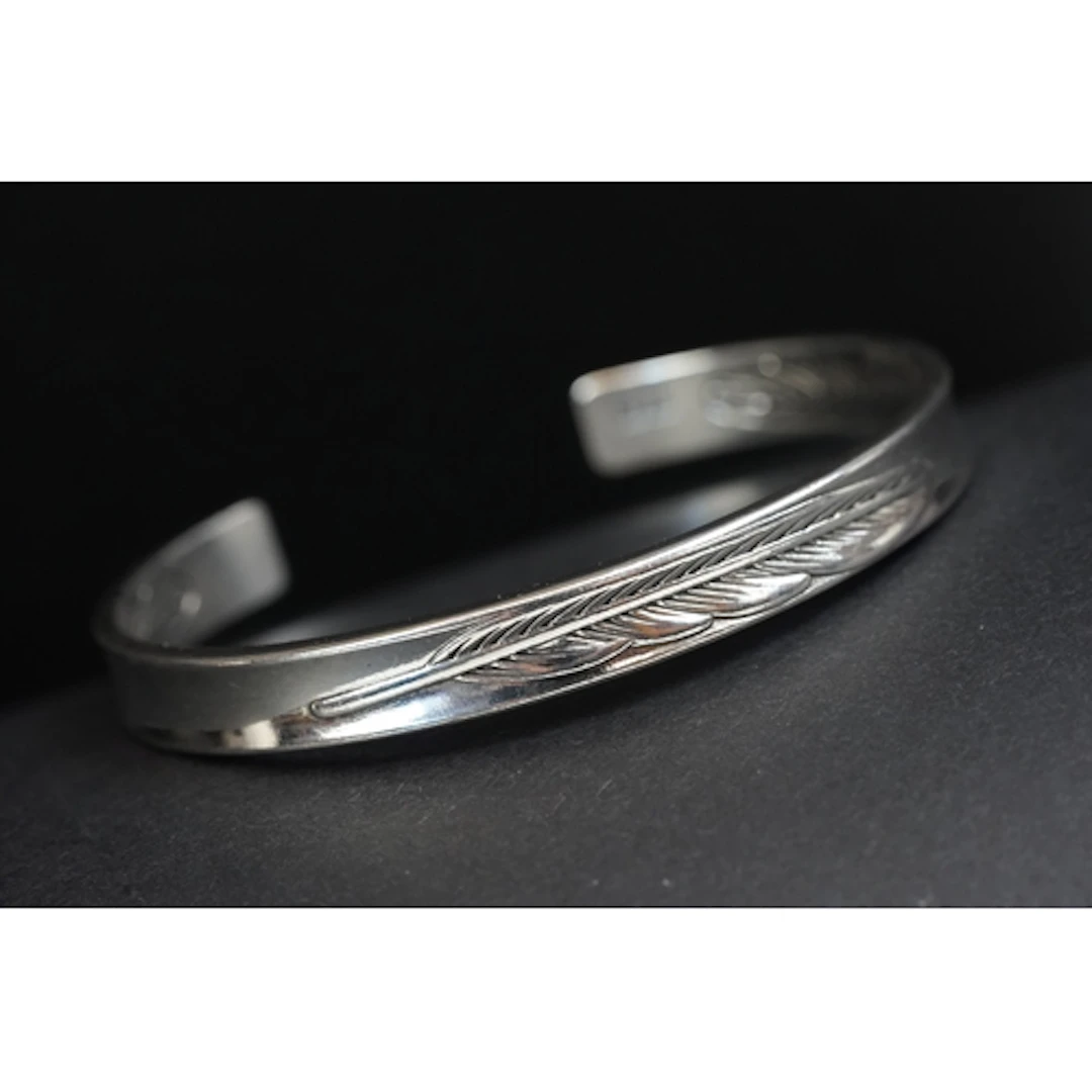 A contemporary silver open backed bangle, feather decoration...
