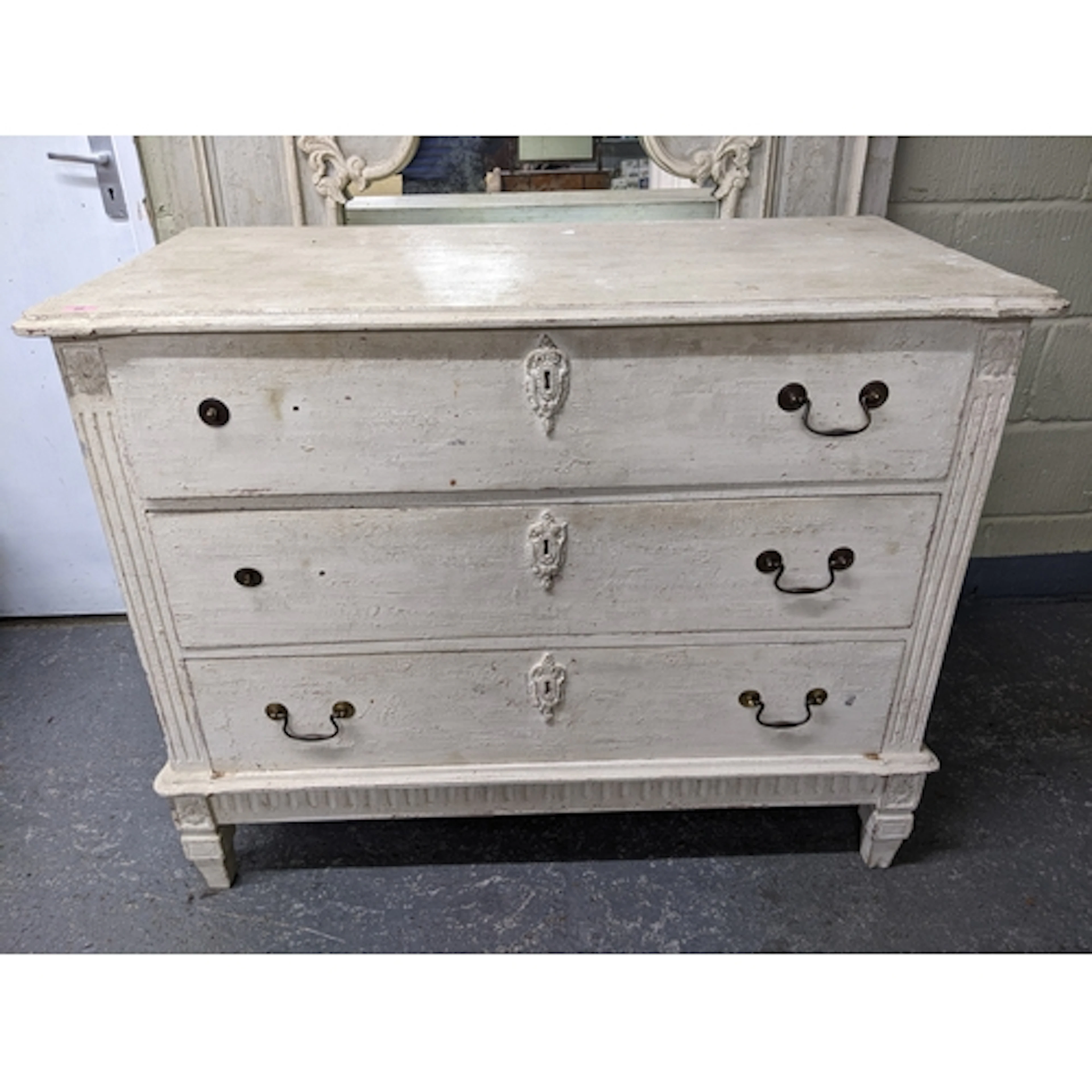 A cream painted chest of three drawers with brass swan neck ...