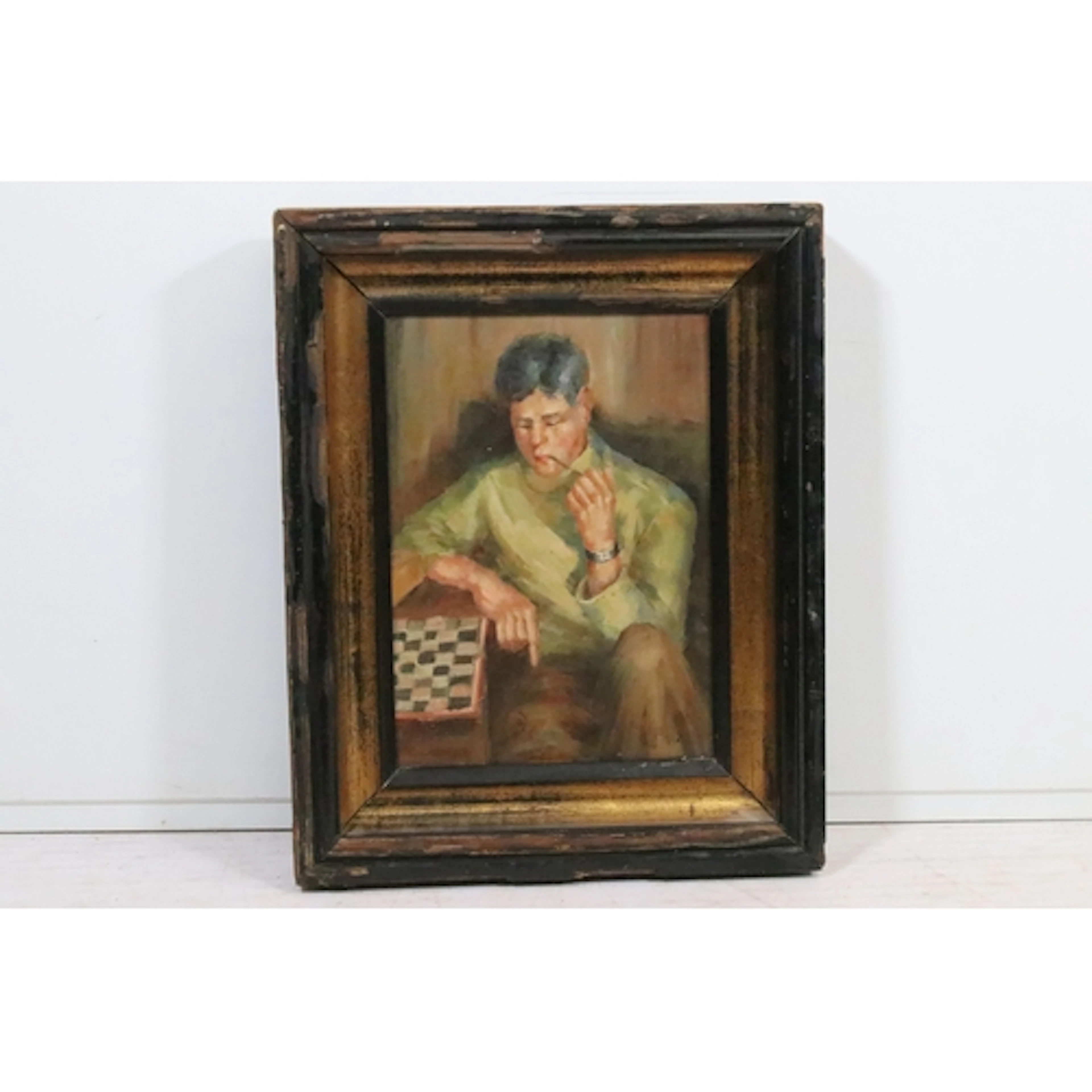 Portrait of a man smoking a pipe, seated beside a chess boar...
