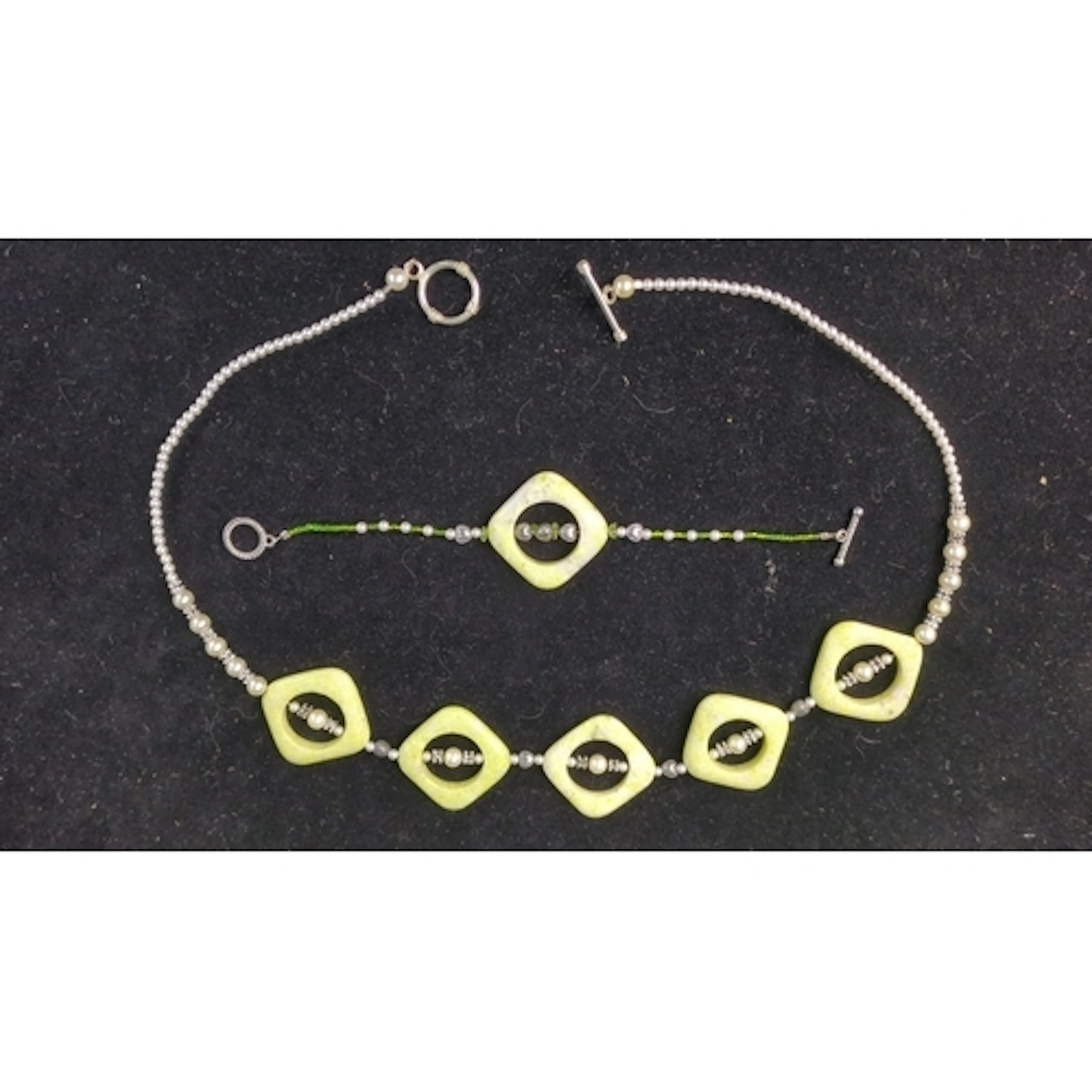 A necklace and matching bracelet composed of pale green open...