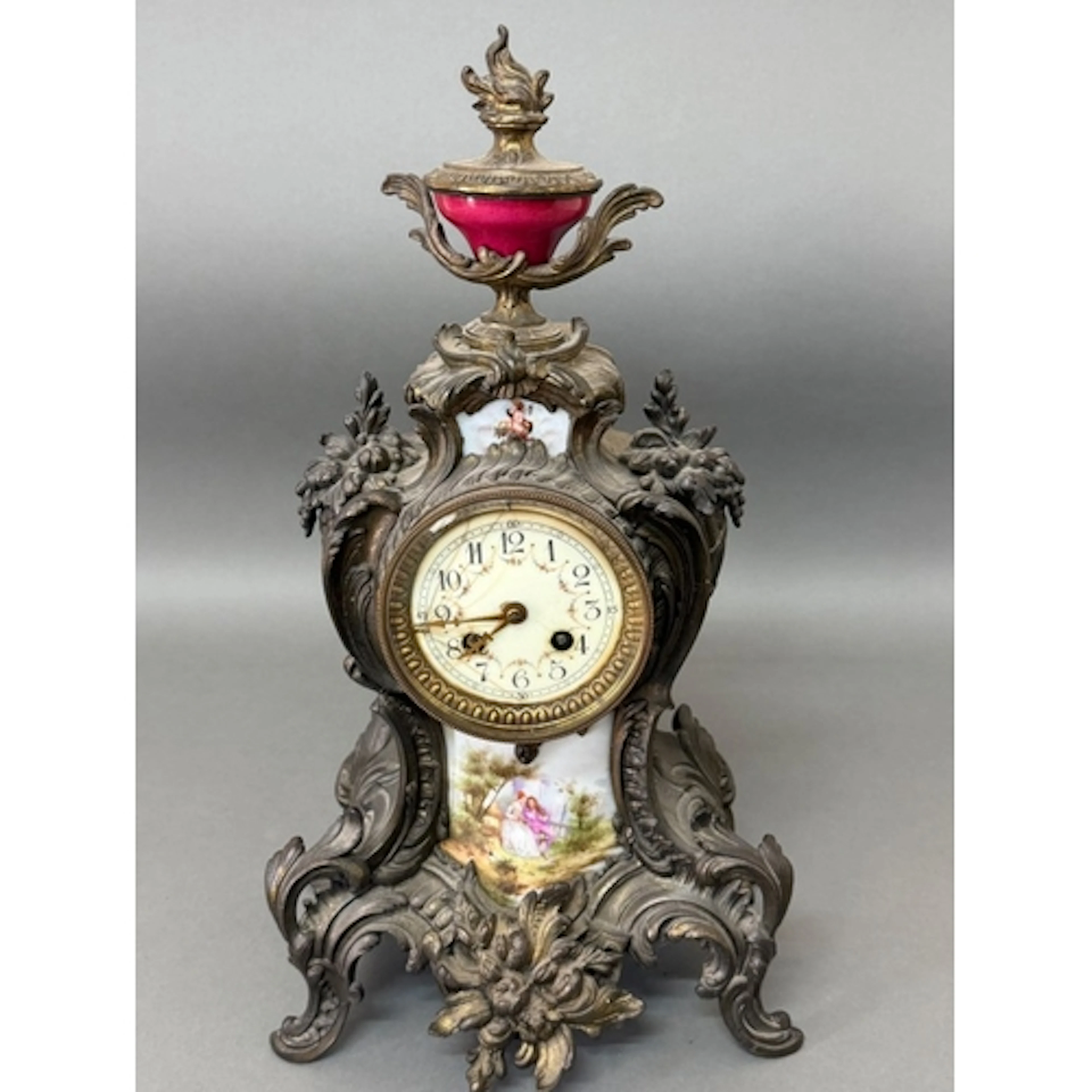 A gilt metal mantel clock in a Roccoco style with porcelain ...