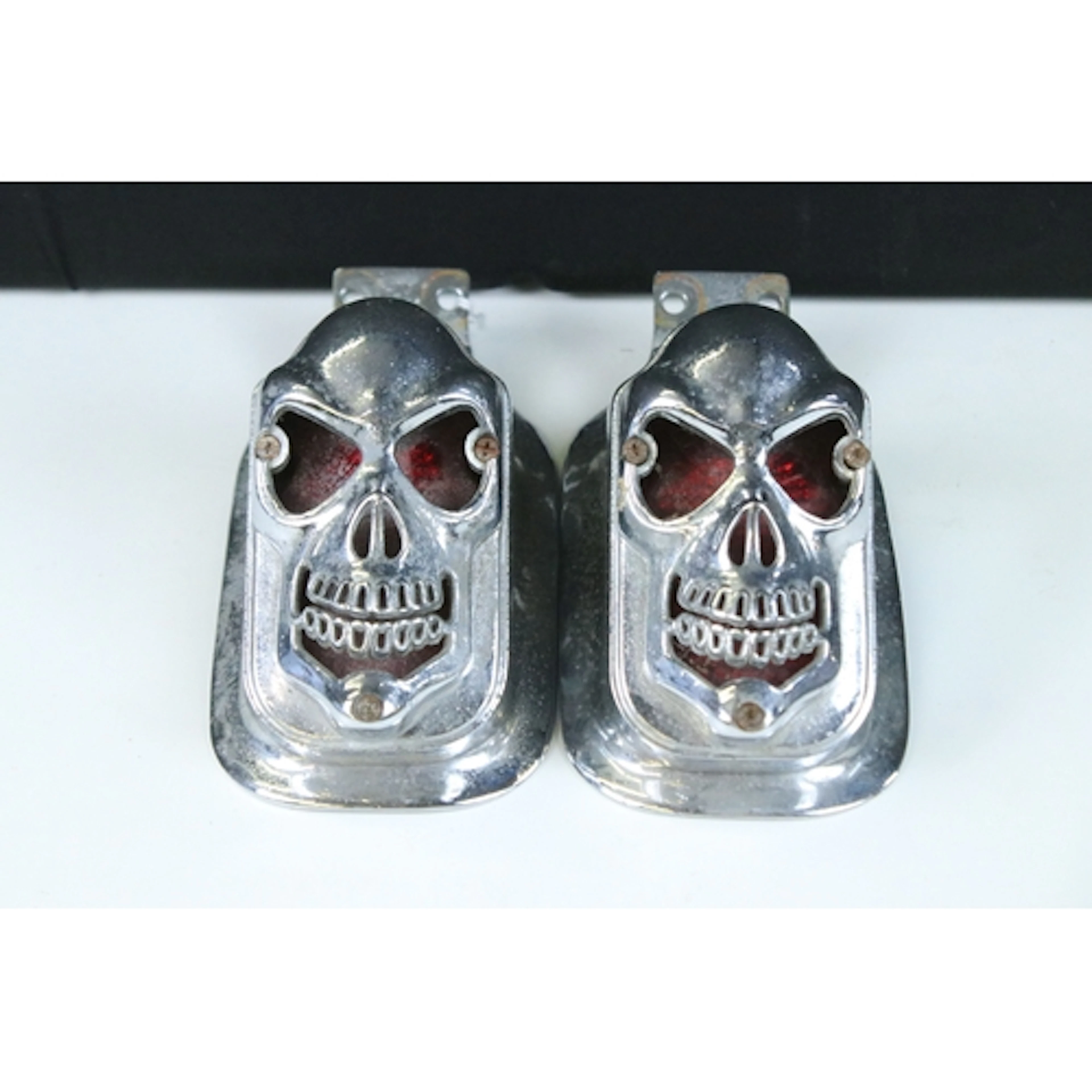 Pair of chrome motorcycle lights in the form of skulls, leng...