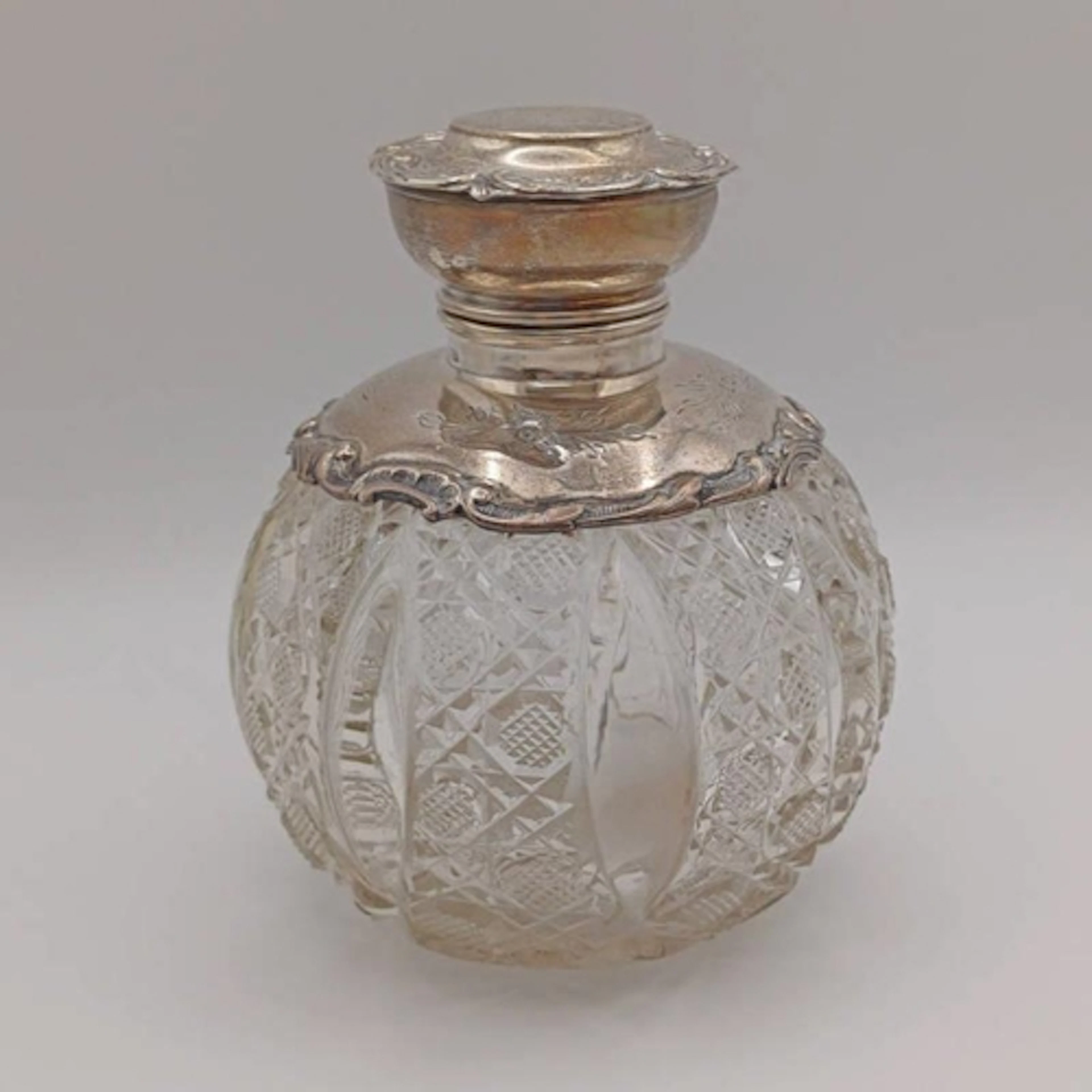A CUT GLASS SILVER MOUNTED SCENT BOTTLE WITH ENGRAVED FLORAL...