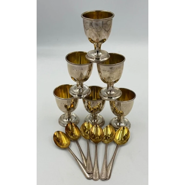 A set of six silver egg cups and spoons with gilt interior b...