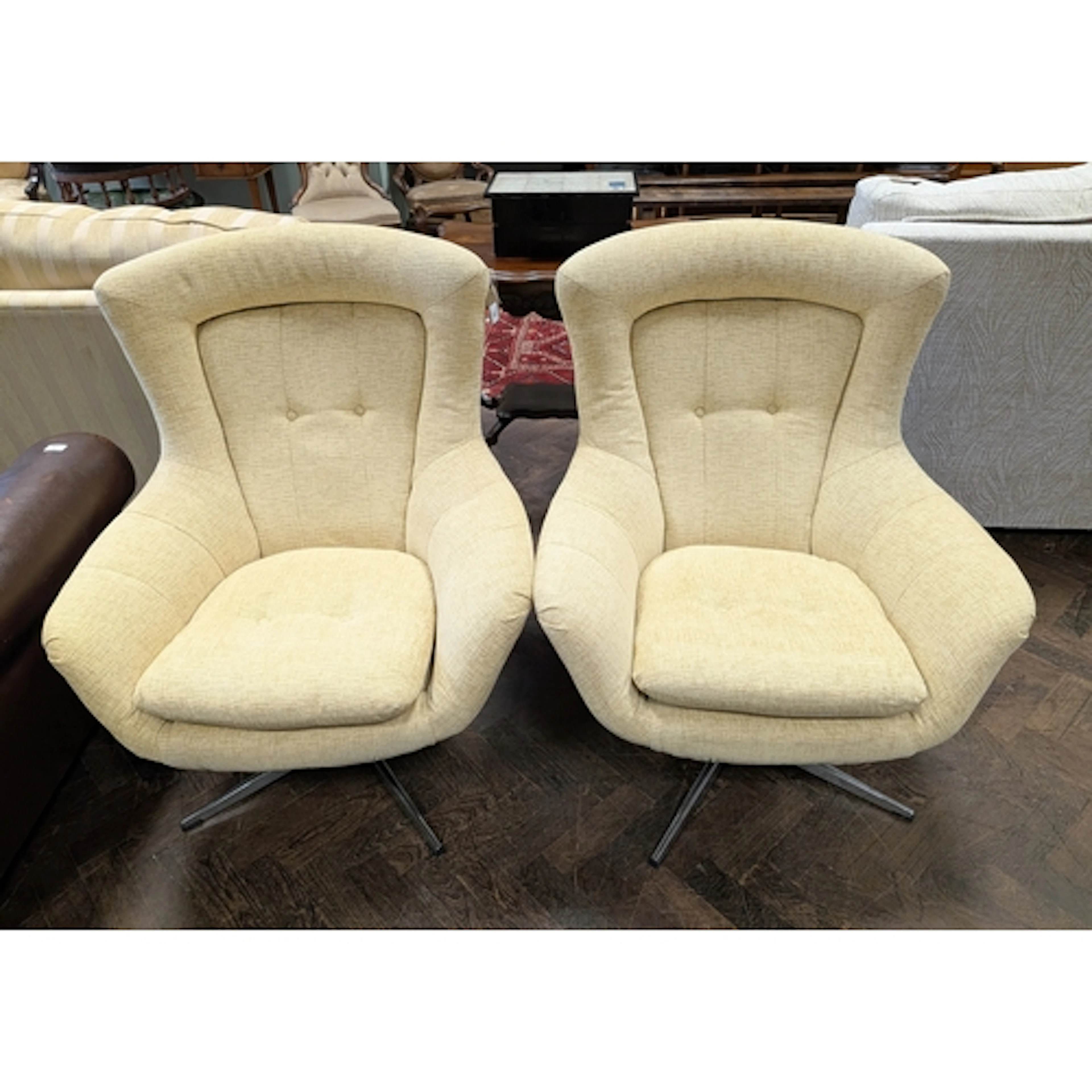 A pair of vintage retro style revolving easy chairs in cream...