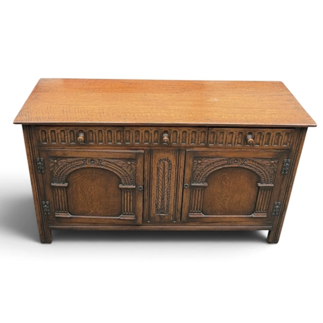 A JACOBEAN STYLE OAK SIDEBOARD With three short drawers over...