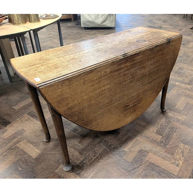 A circular antique oak drop leaf dining table on pad feet, 4...