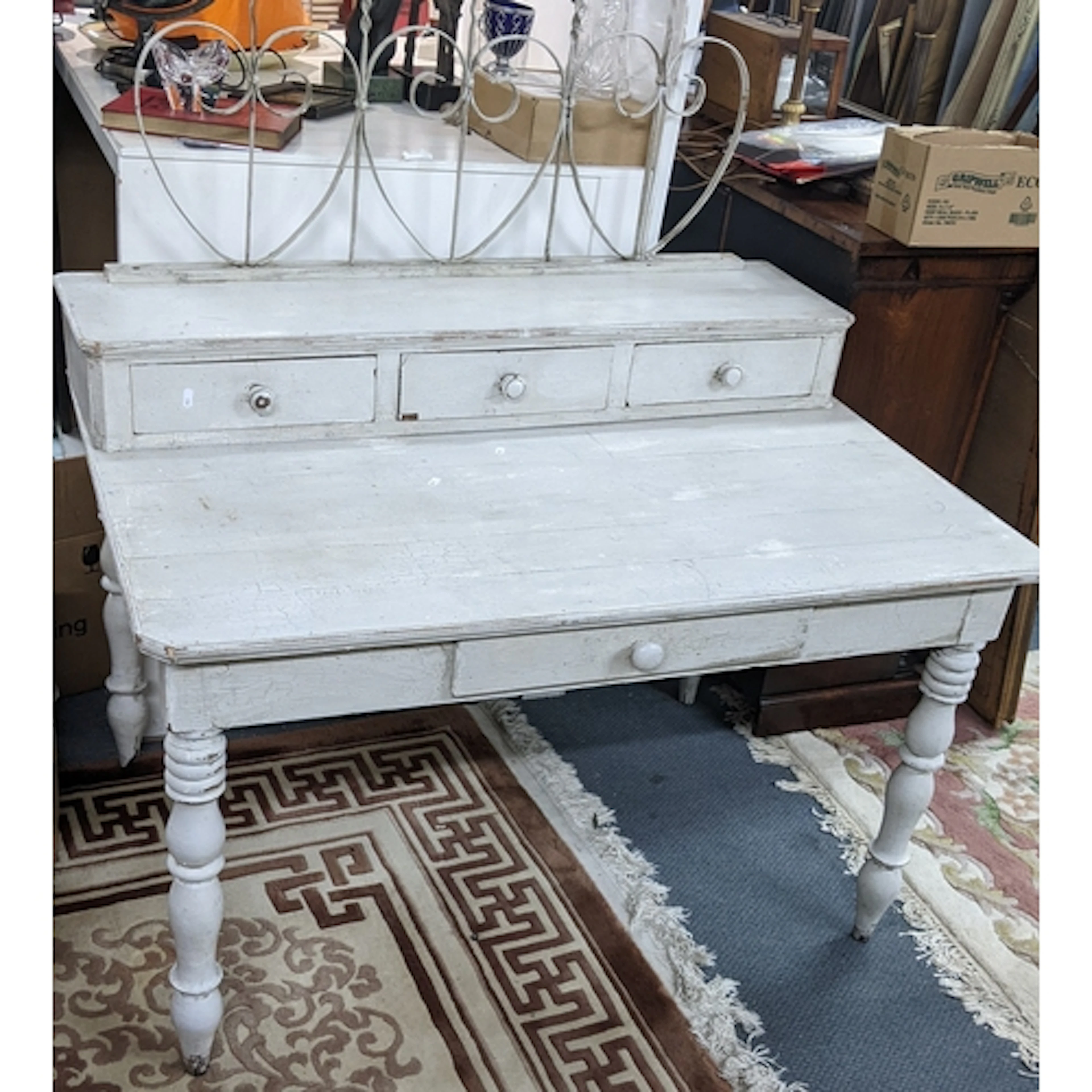 A painted shabby chic desk having iron heart shaped back abo...