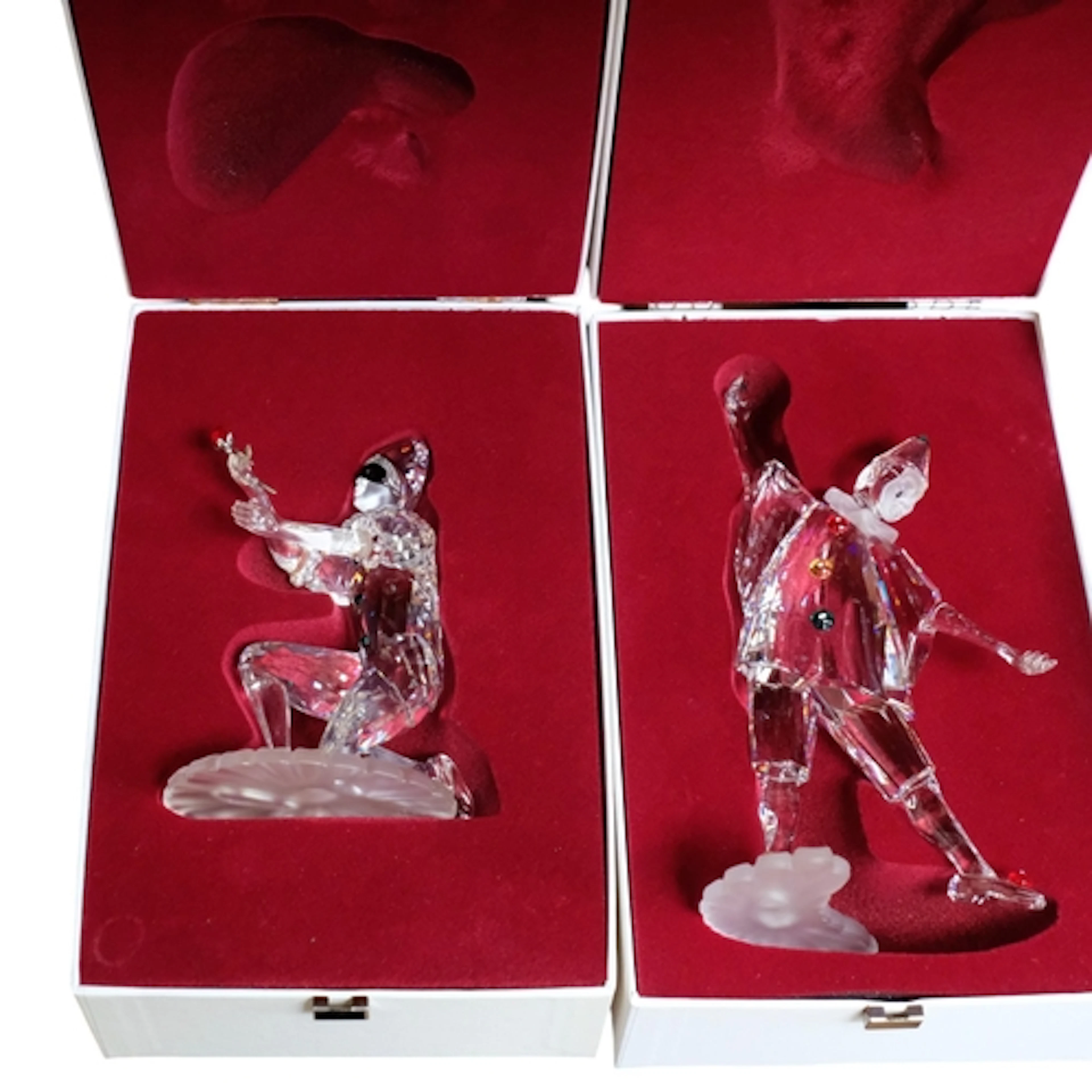 A pair of boxed Swarovski crystal figures, Pierrot and Colom...