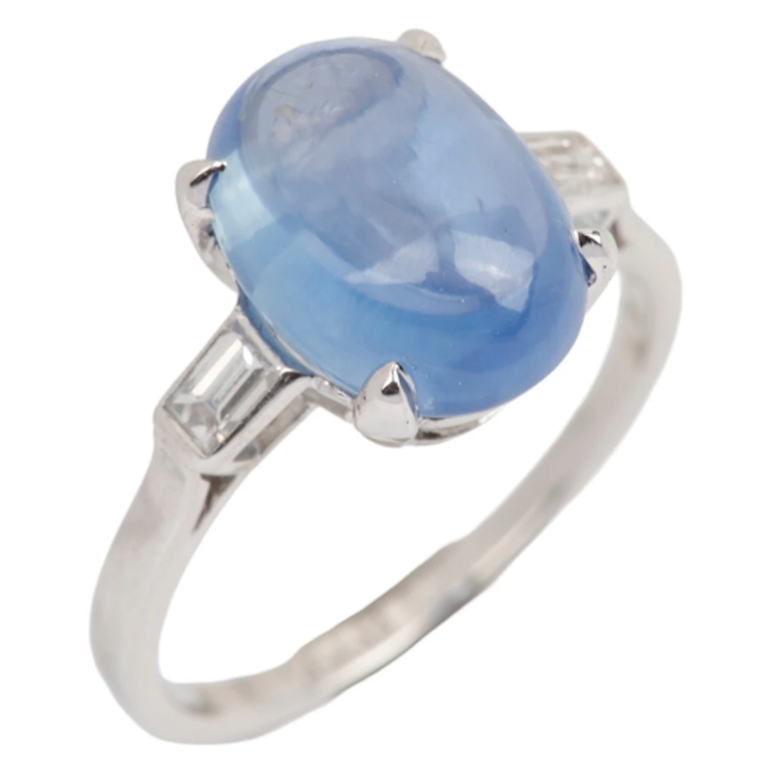 A sapphire and diamond ring, claw-set with a cabochon sapphi...
