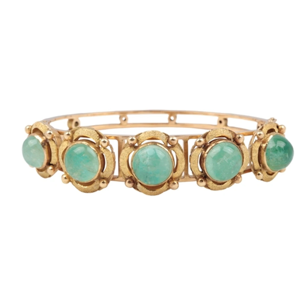 A gold and emerald bangle, of hinged design, set to the fron...