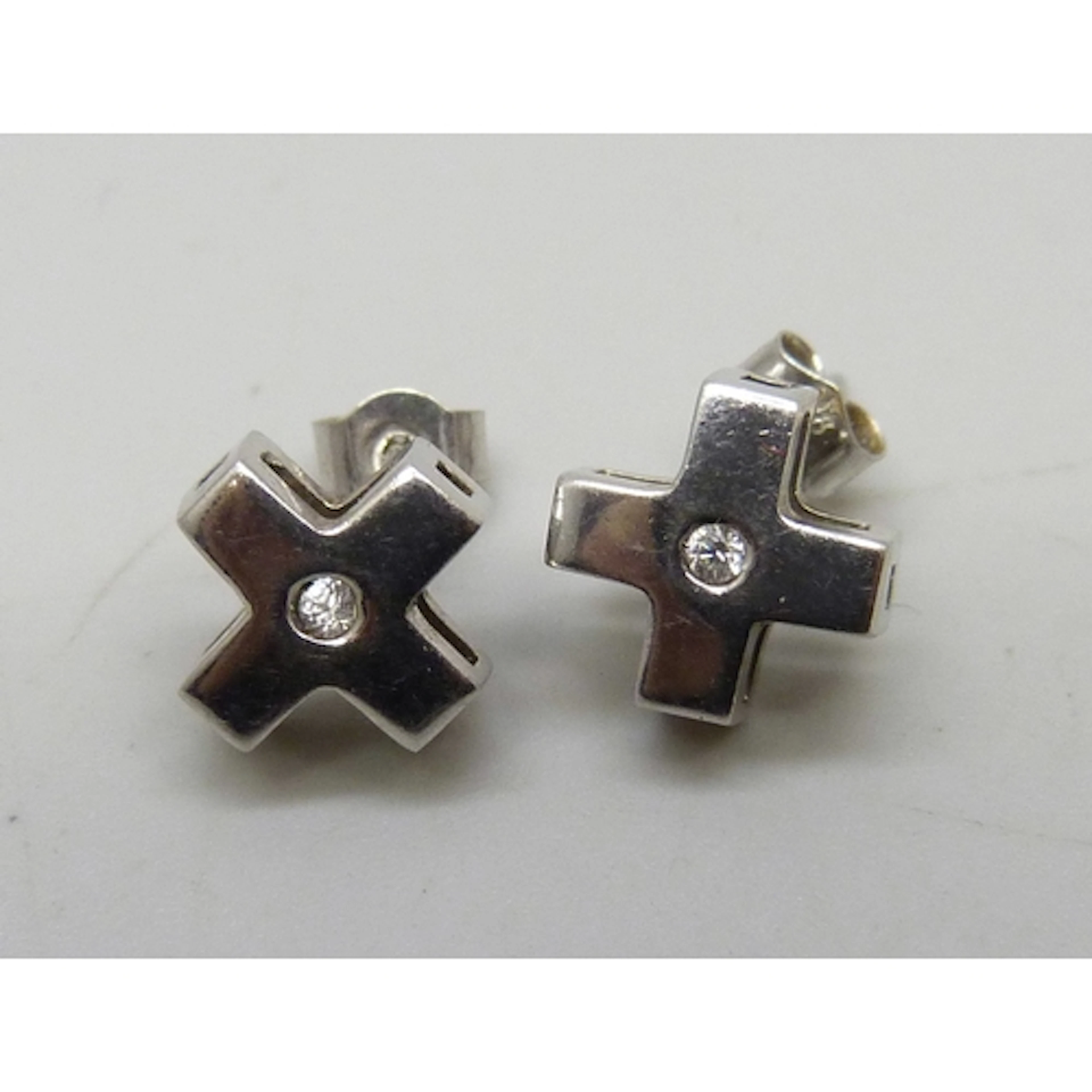 A pair of 9ct white gold cross design earrings set with whit...