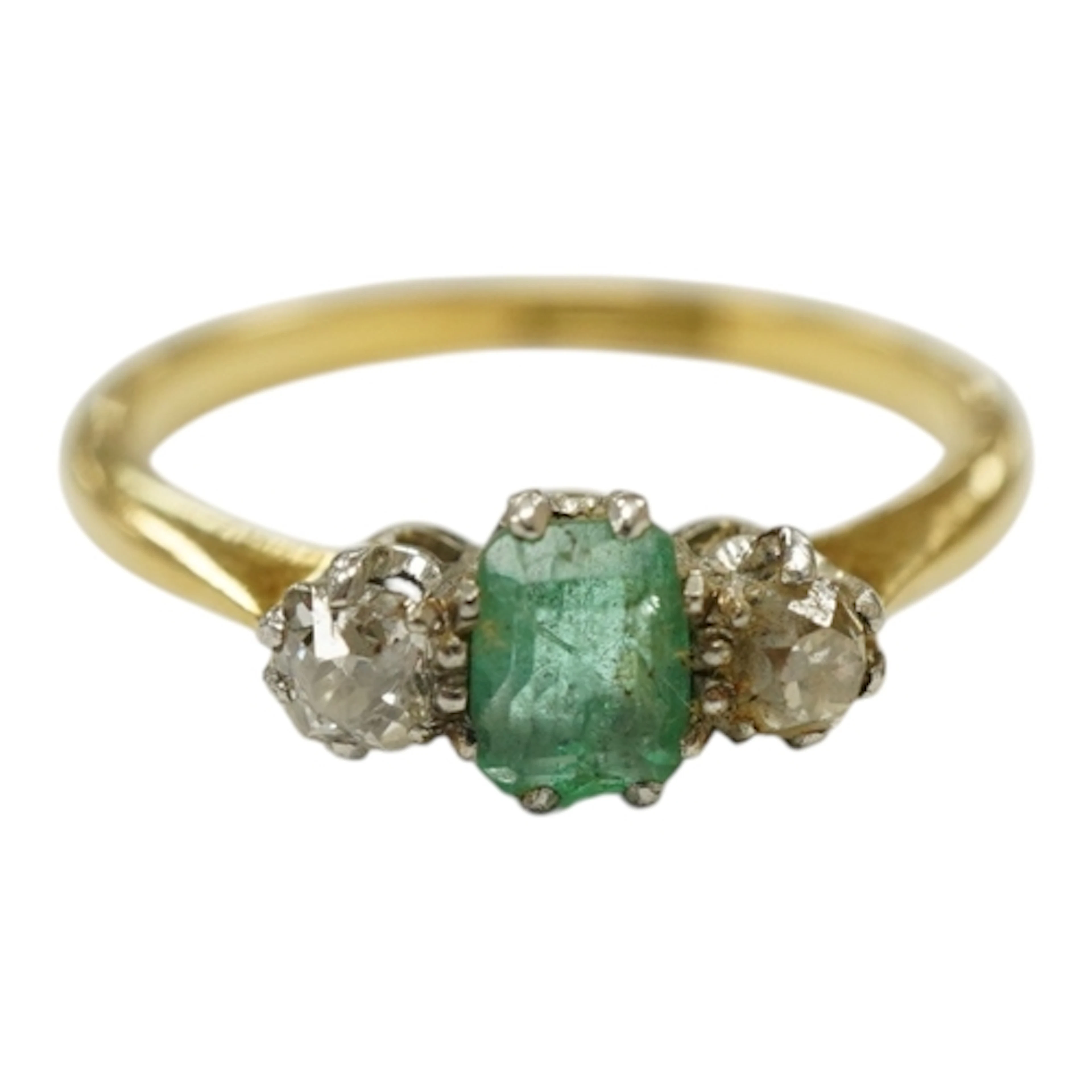 A yellow metal, emerald and diamond set three stone ring, st...