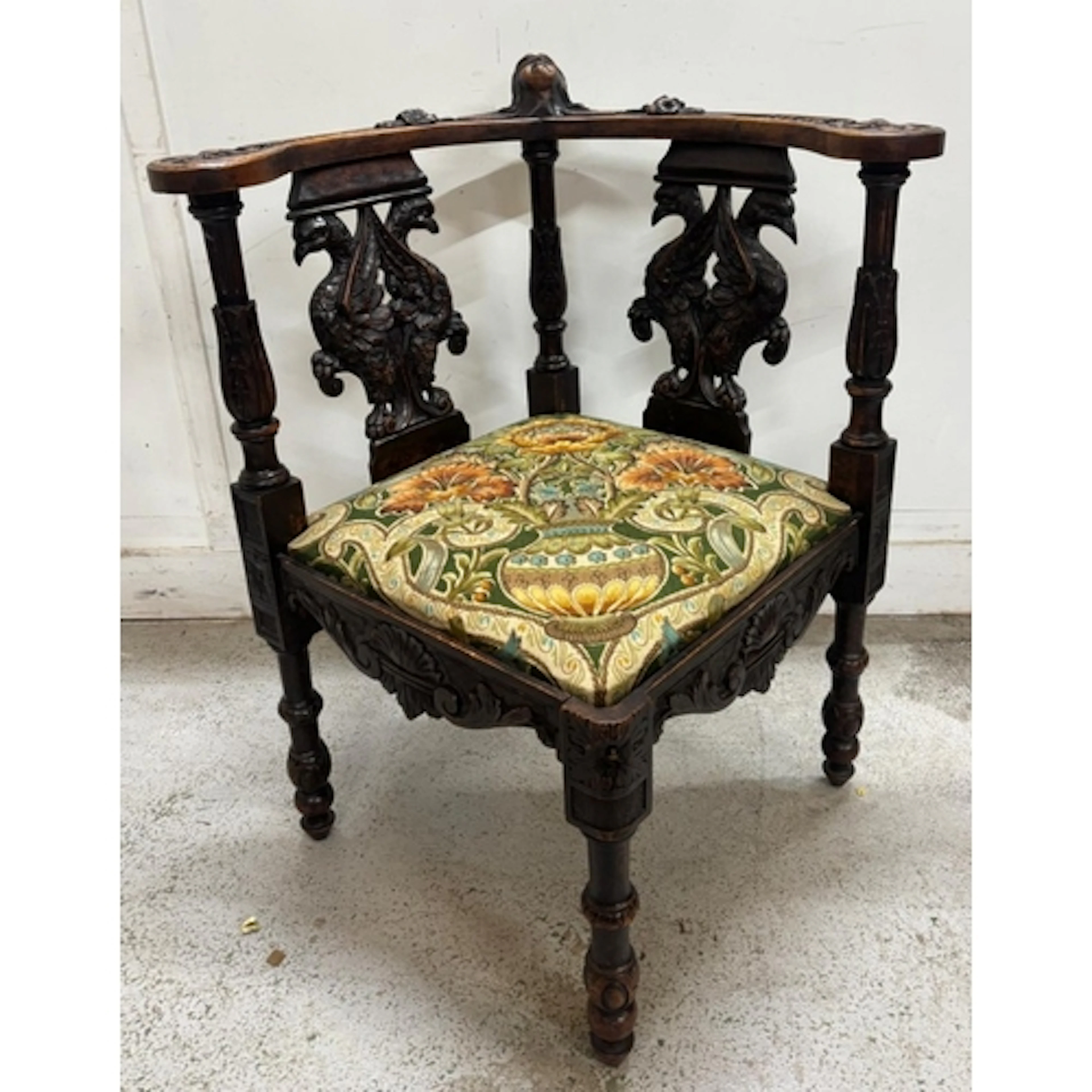 A carved wooden corner chair featuring detailed mythological...