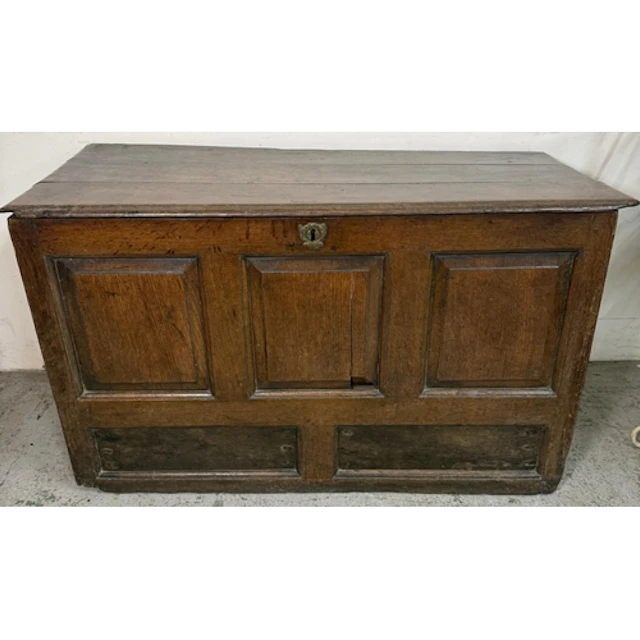 An oak coffer with hinged plank lid and three panels to fron...