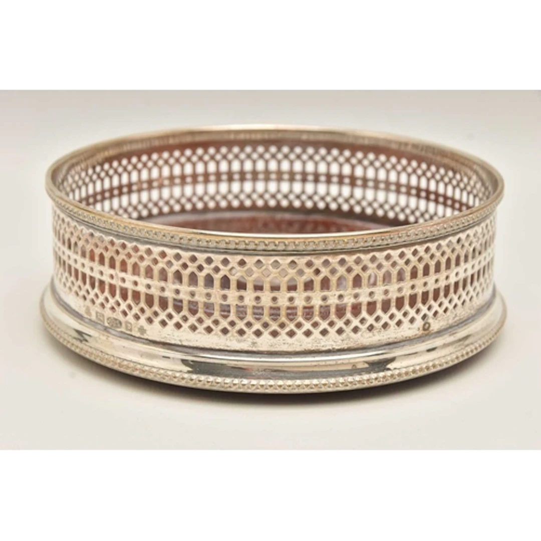 AN ELIZABETH II SILVER BOTTLE COASTER, circular wooden base ...