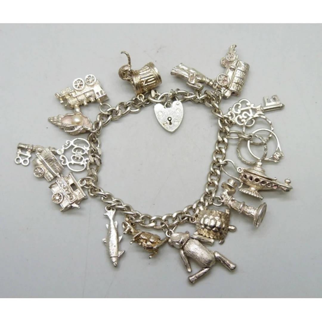 A silver charm bracelet with a collection of silver and whit...