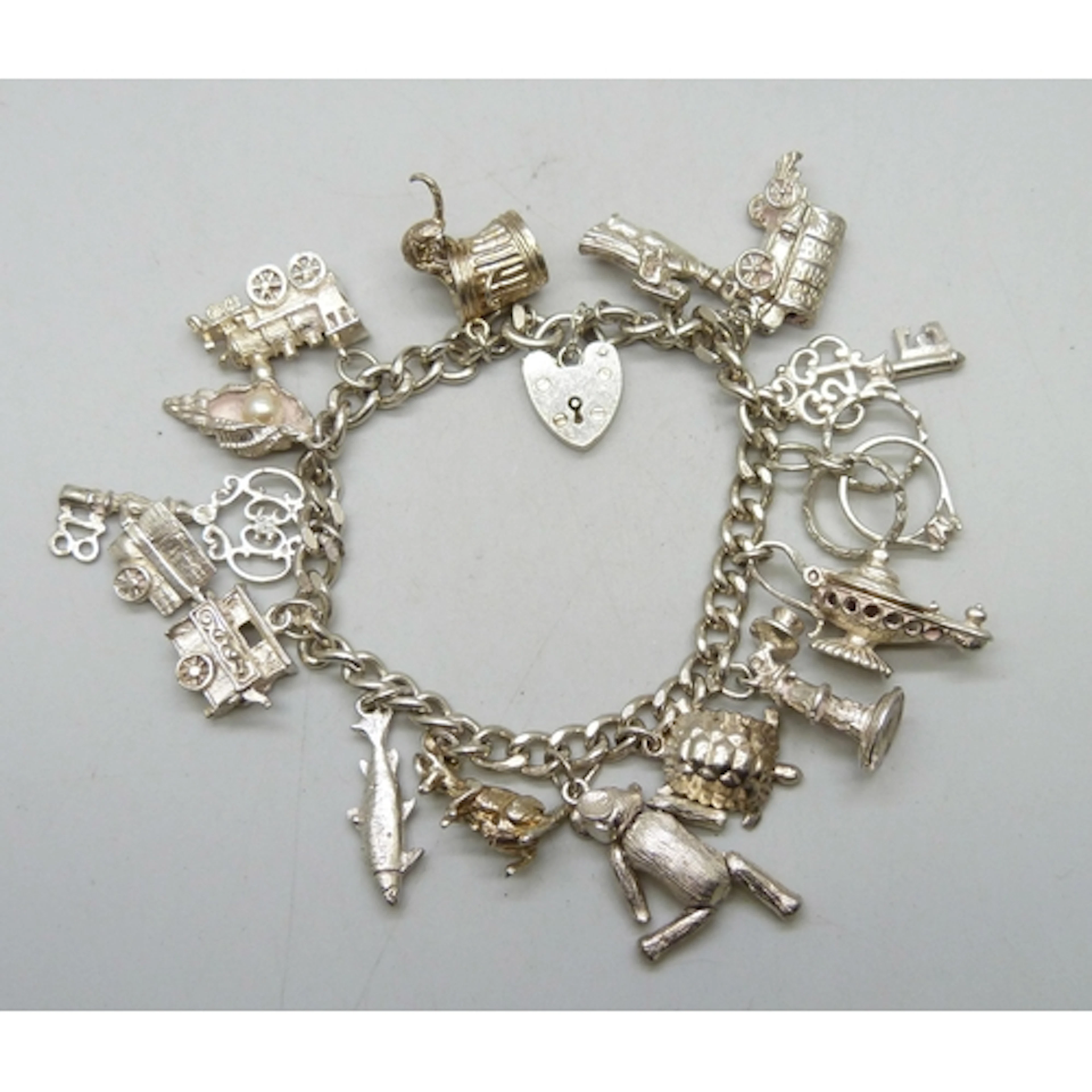 A silver charm bracelet with a collection of silver and whit...