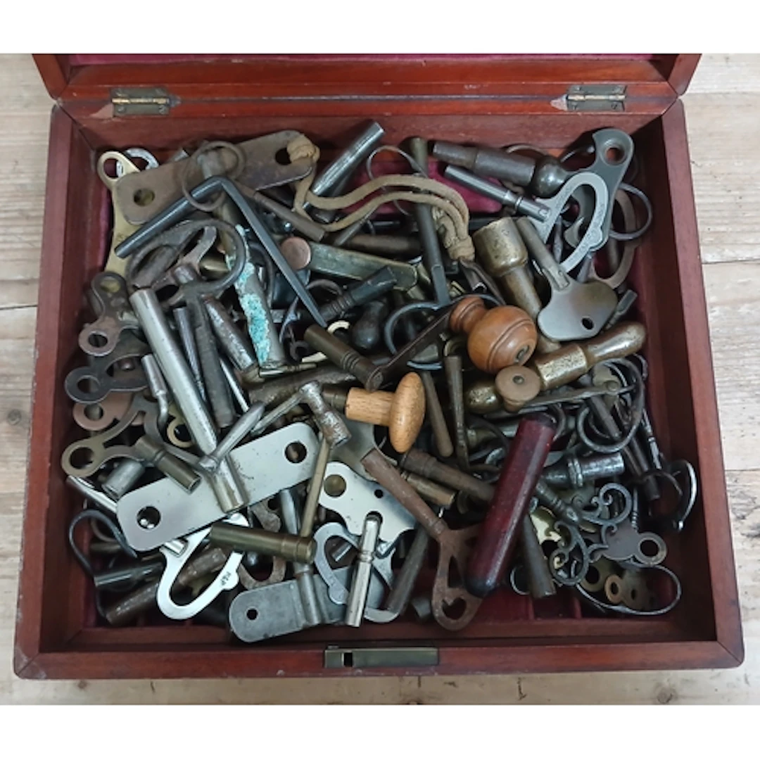 A lidded wooden box of assorted clock keys.
