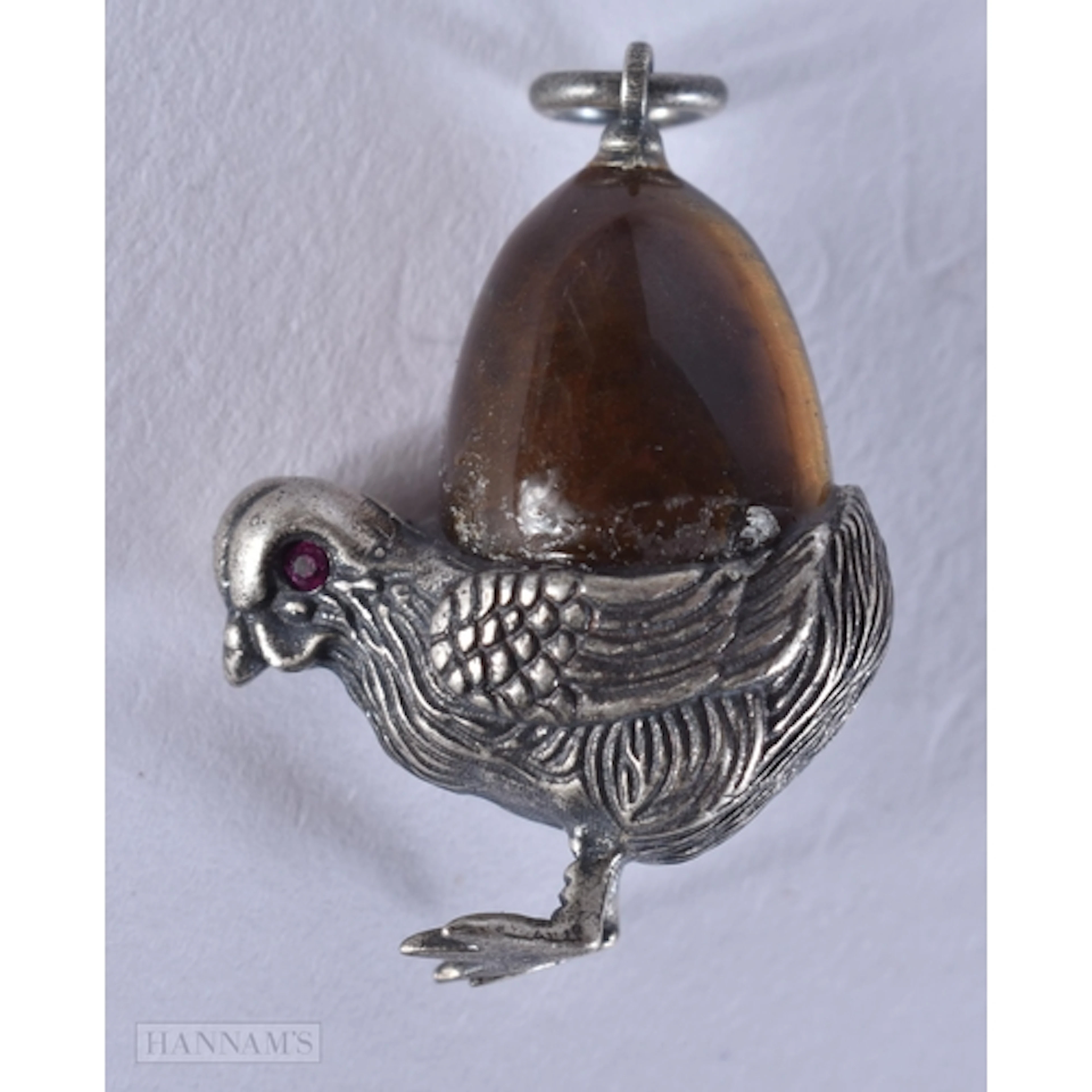 A CONTINENTAL CHICK PENDANT WITH A TIGERS EYE EGG. 3.1 x 2.1...