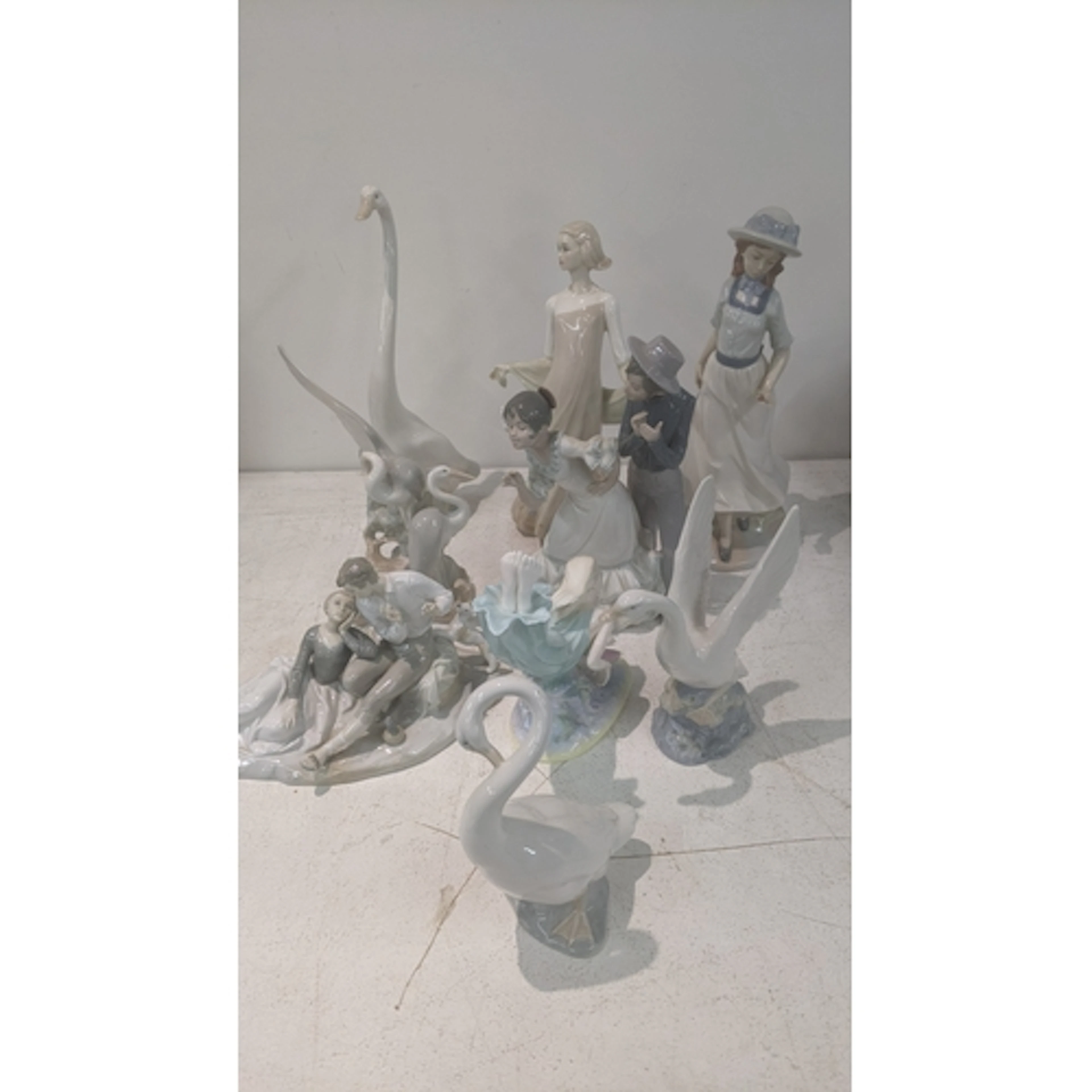 A group of porcelain figures to include a Nao goose, a Nadal...
